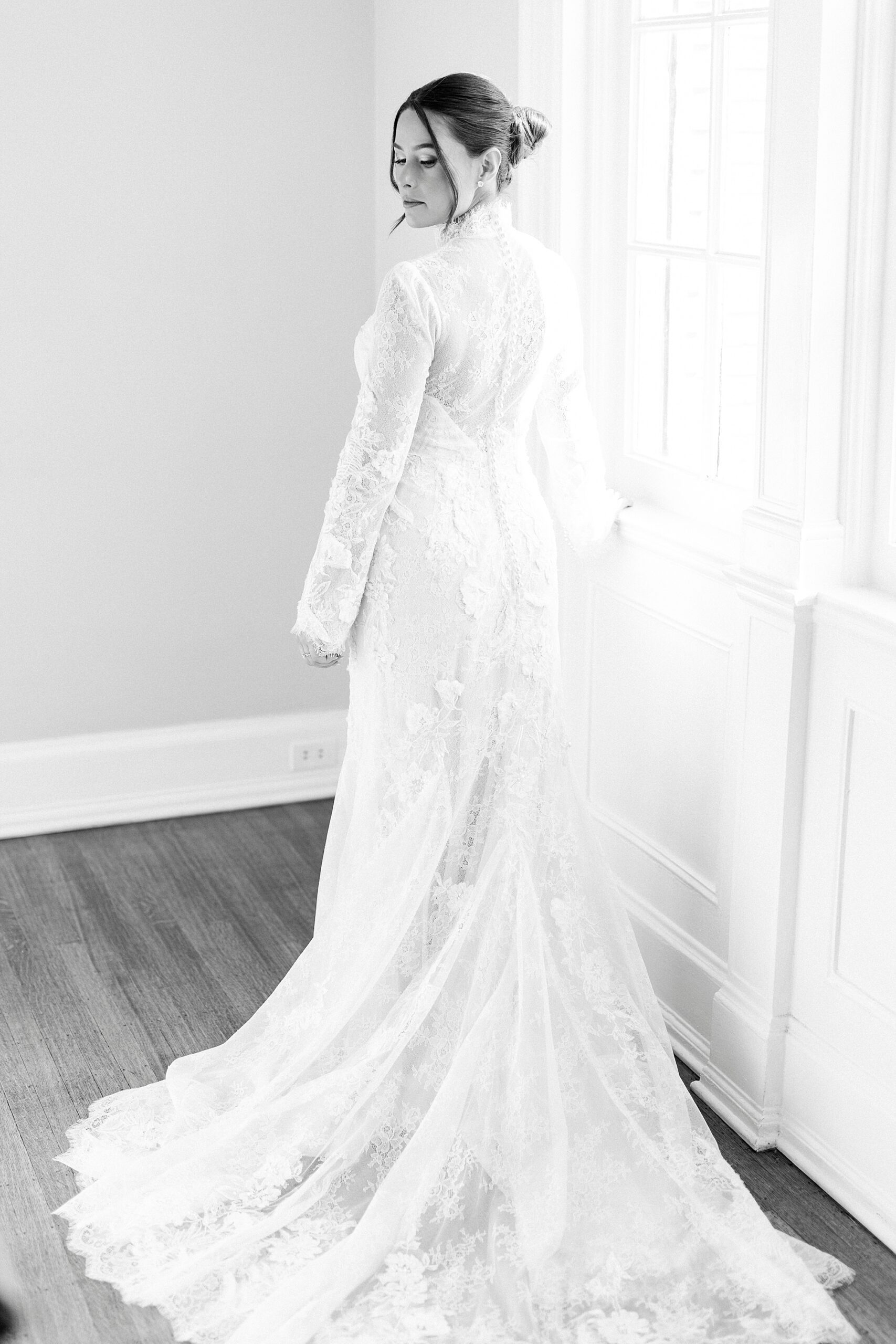 bride stands by window in wedding gown with lace top