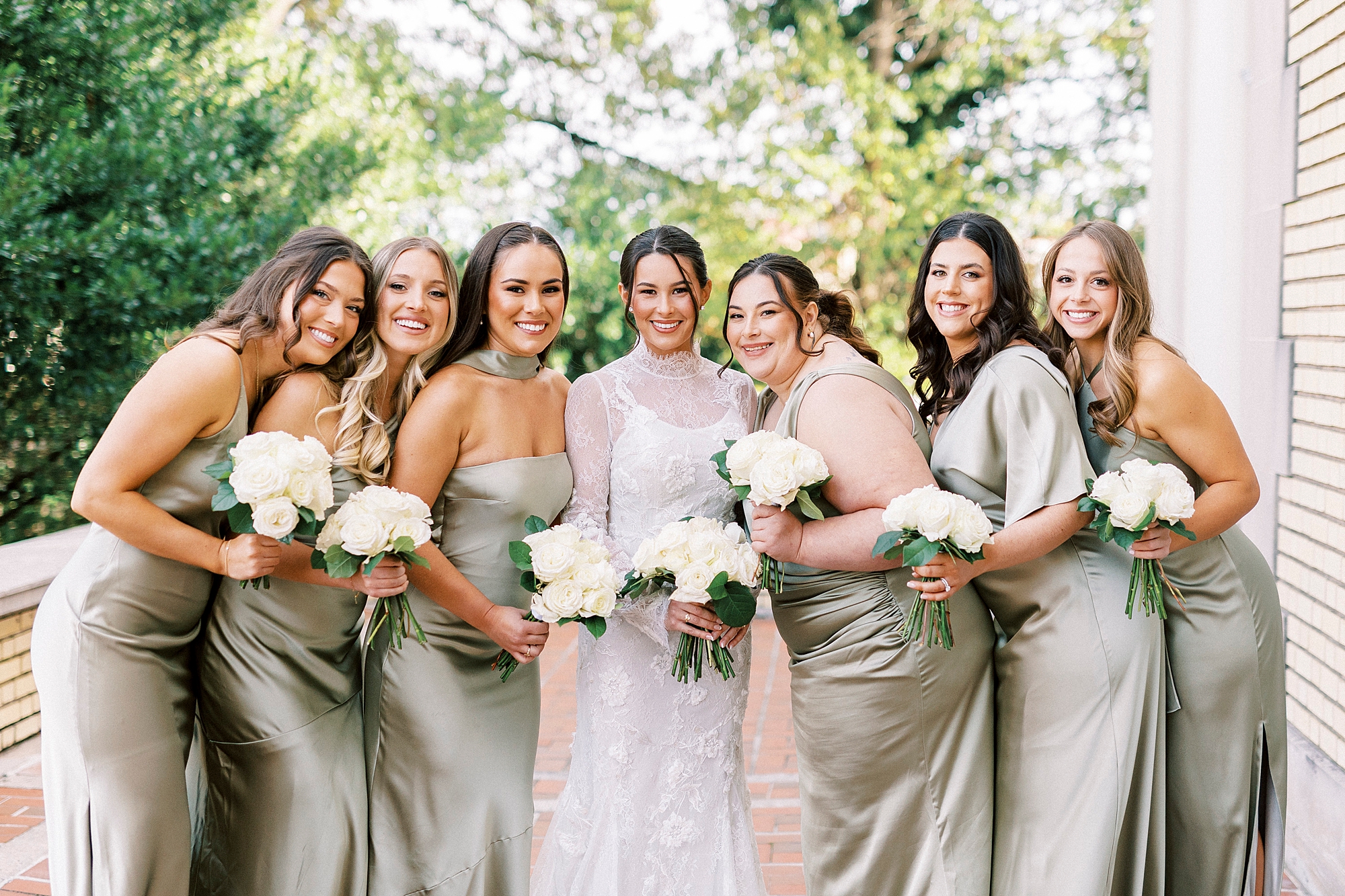 bride hugs bridesmaids in sage green mismatched gowns