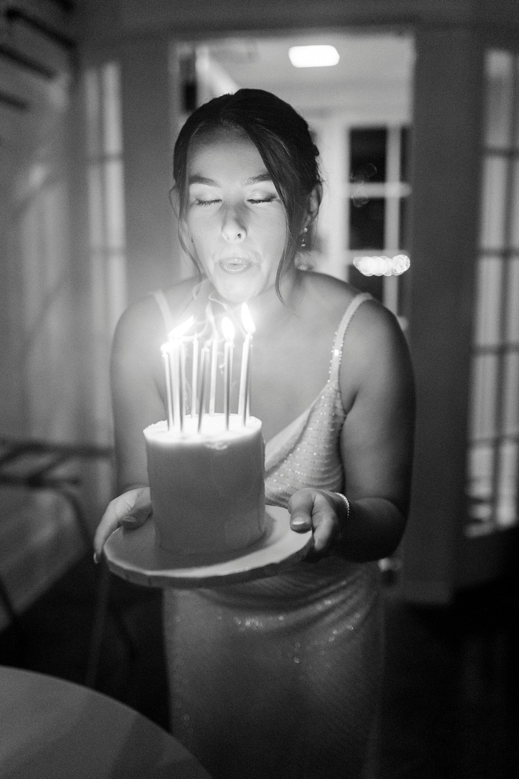 bride holds small cake blowing out thin candles