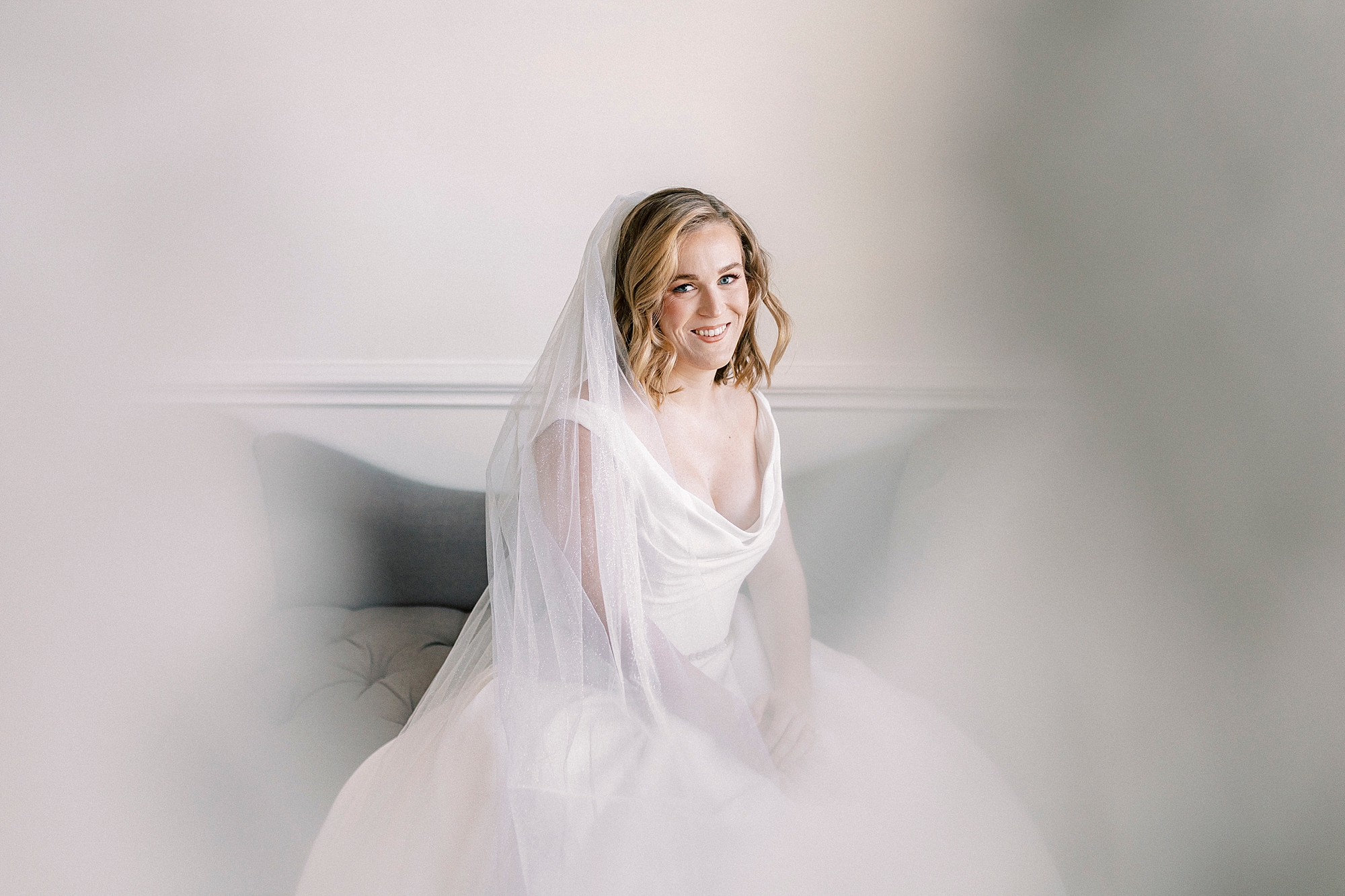 bride sits on green velvet couch during classic bridal portraits at Spark Mansion
