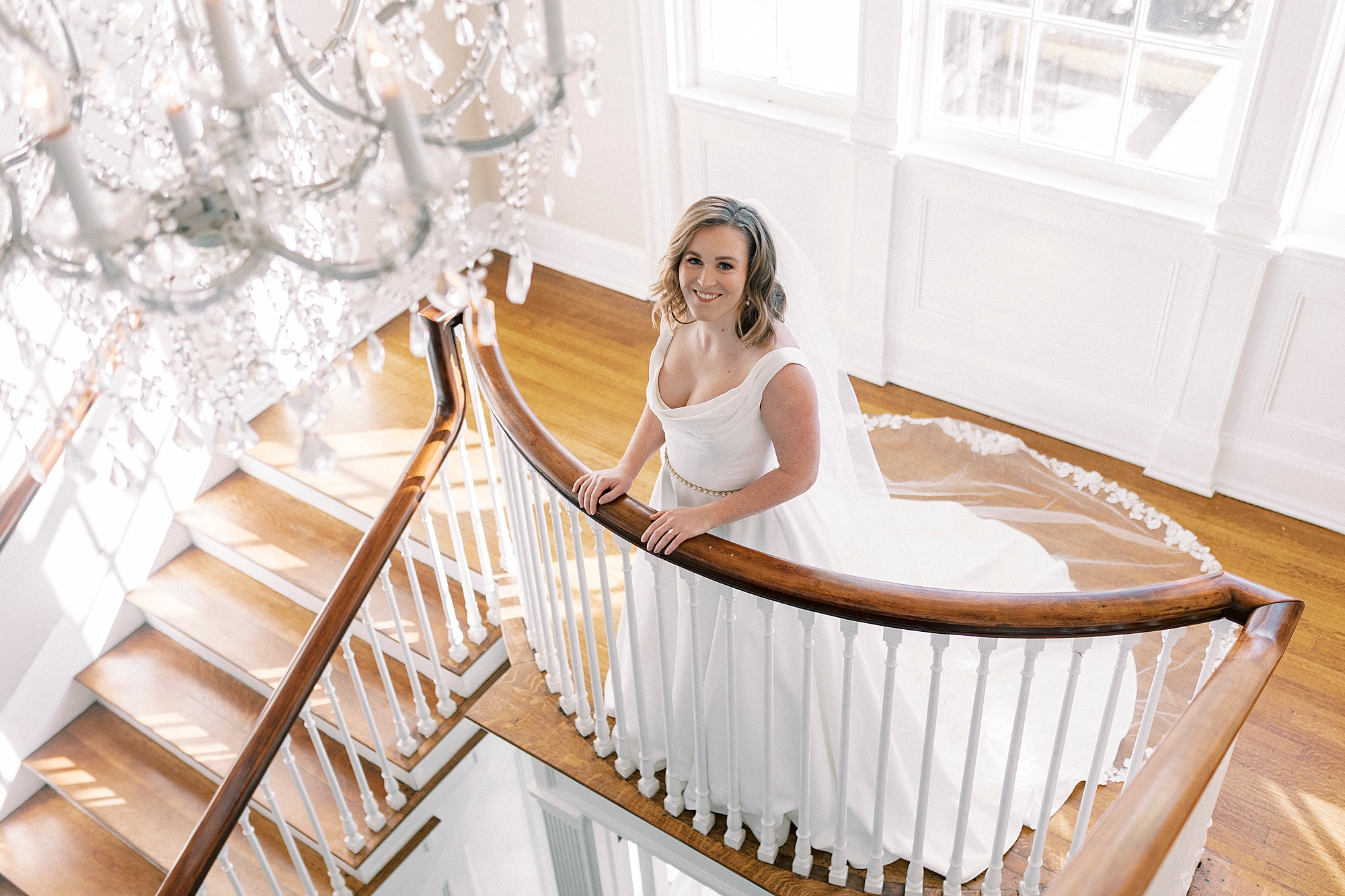 bride stands on landing of staircase inside Separk Mansion in Justin Alexander wedding gown