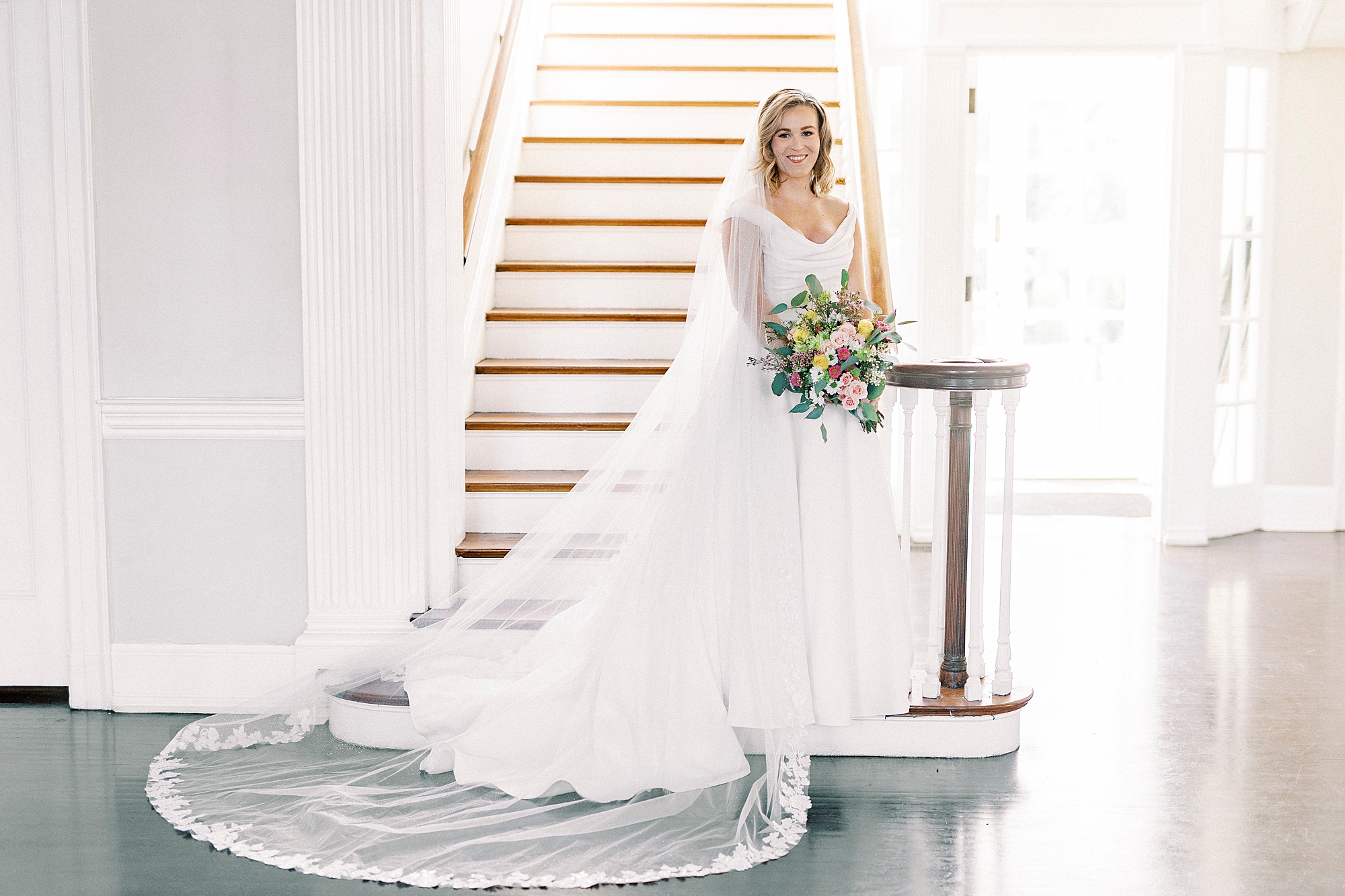 bride stands on landing of staircase inside Separk Mansion in Justin Alexander wedding gown