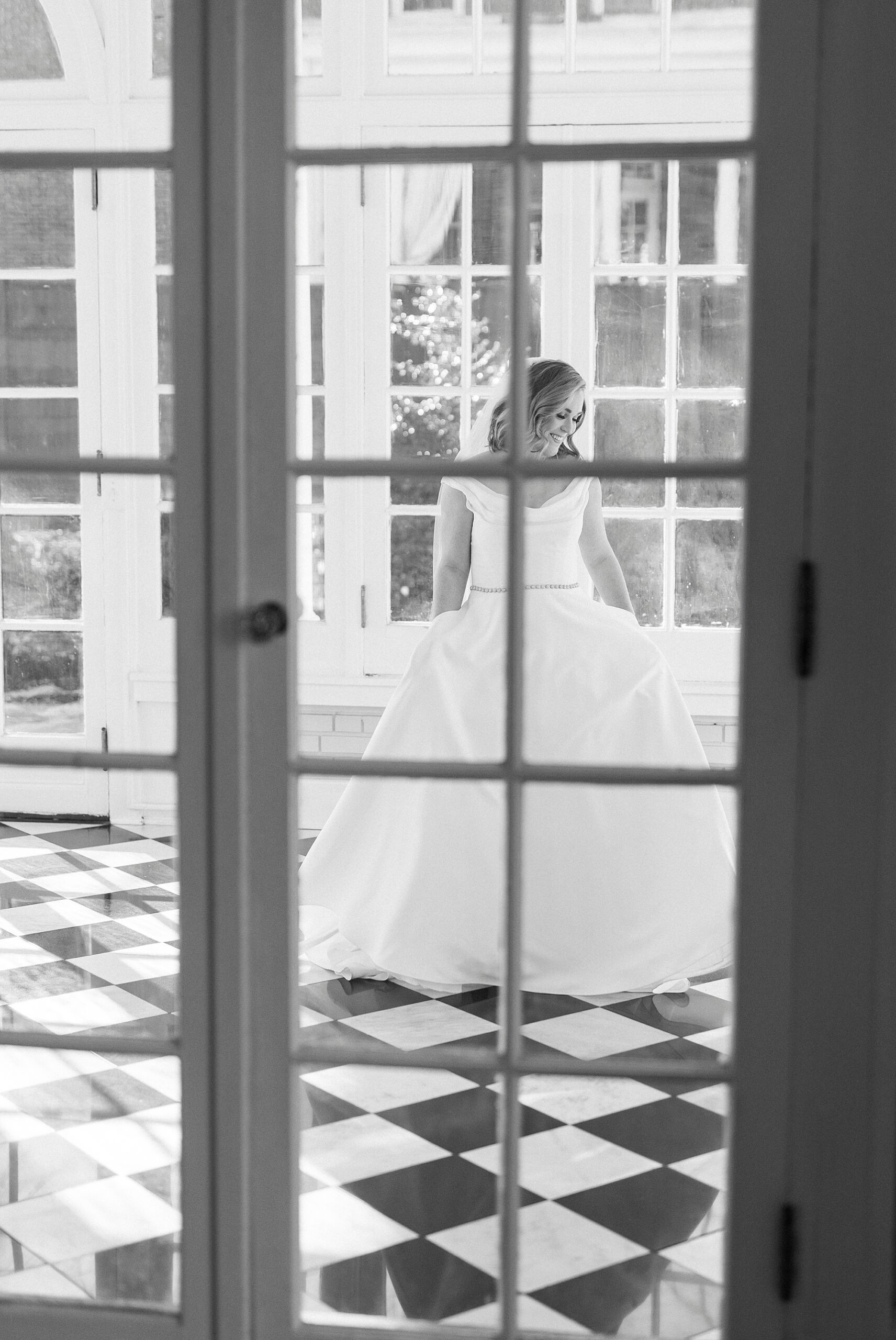 photo of bride twirling through window in room with black and white tile floor at Separk Mansion