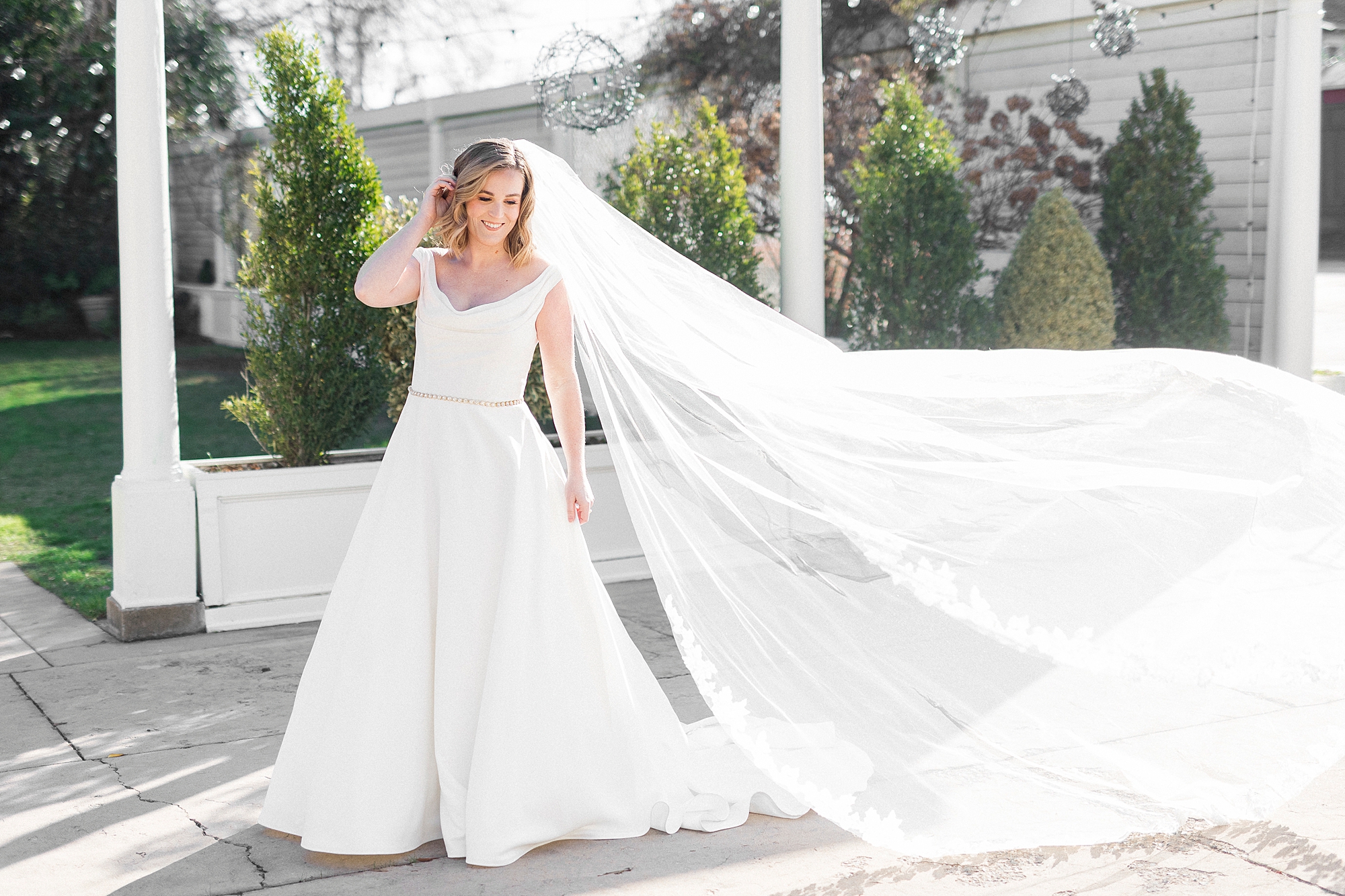 bride stands under awning at Separk Mansion with veil floating behind her