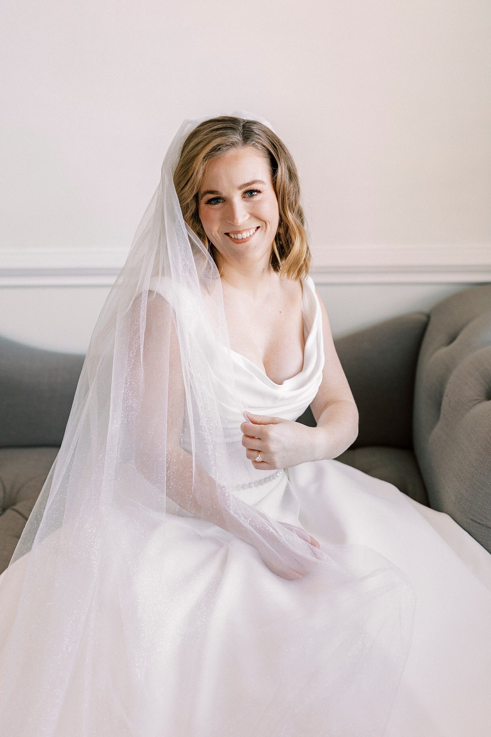 bride sits on green couch during classic bridal portraits at Spark Mansion
