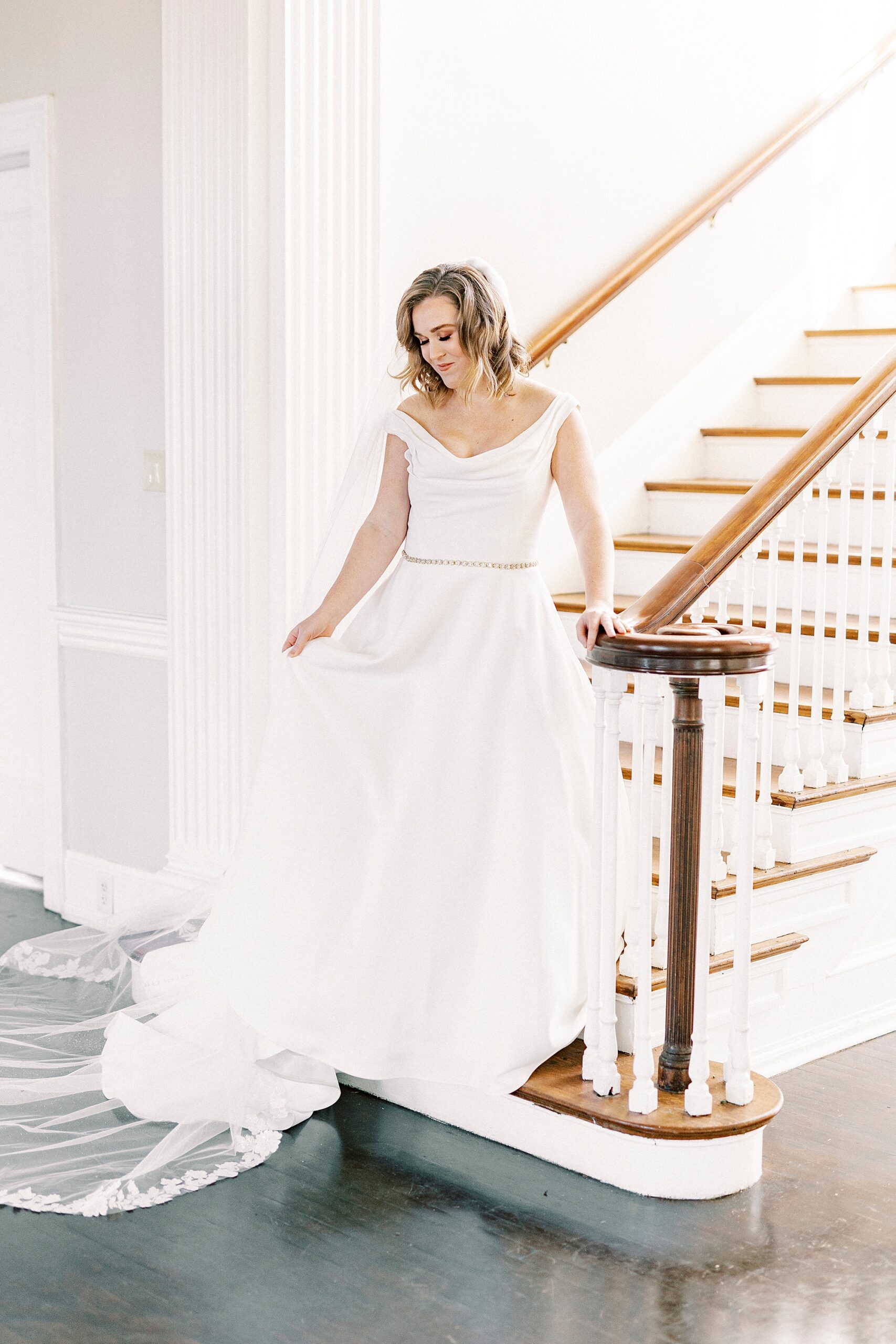bride stands on landing of staircase inside Separk Mansion in Justin Alexander wedding gown