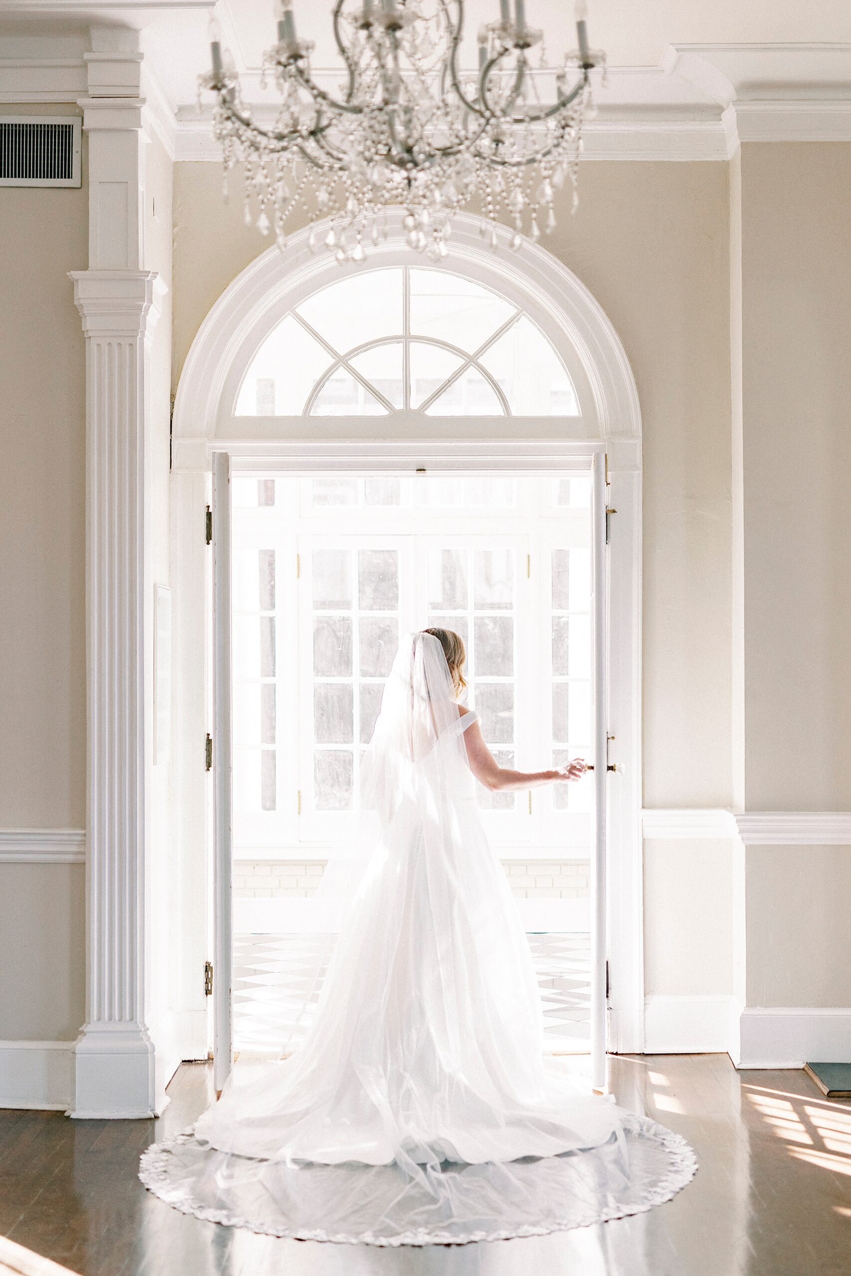 bride stands in doorway at Separk Mansion holding frame