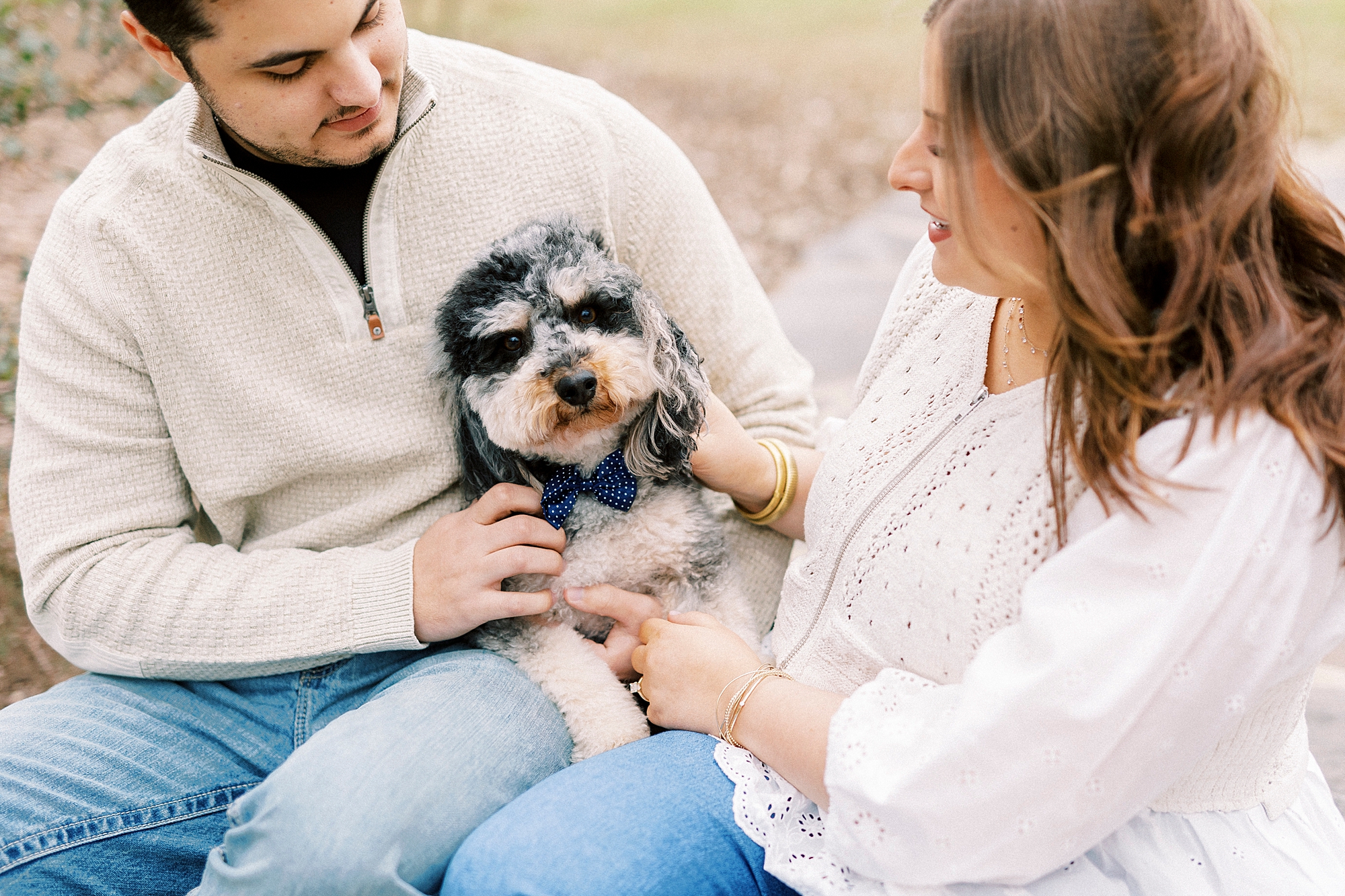 couple sits with small dog on laps during engagement session at Morning Glory Farm