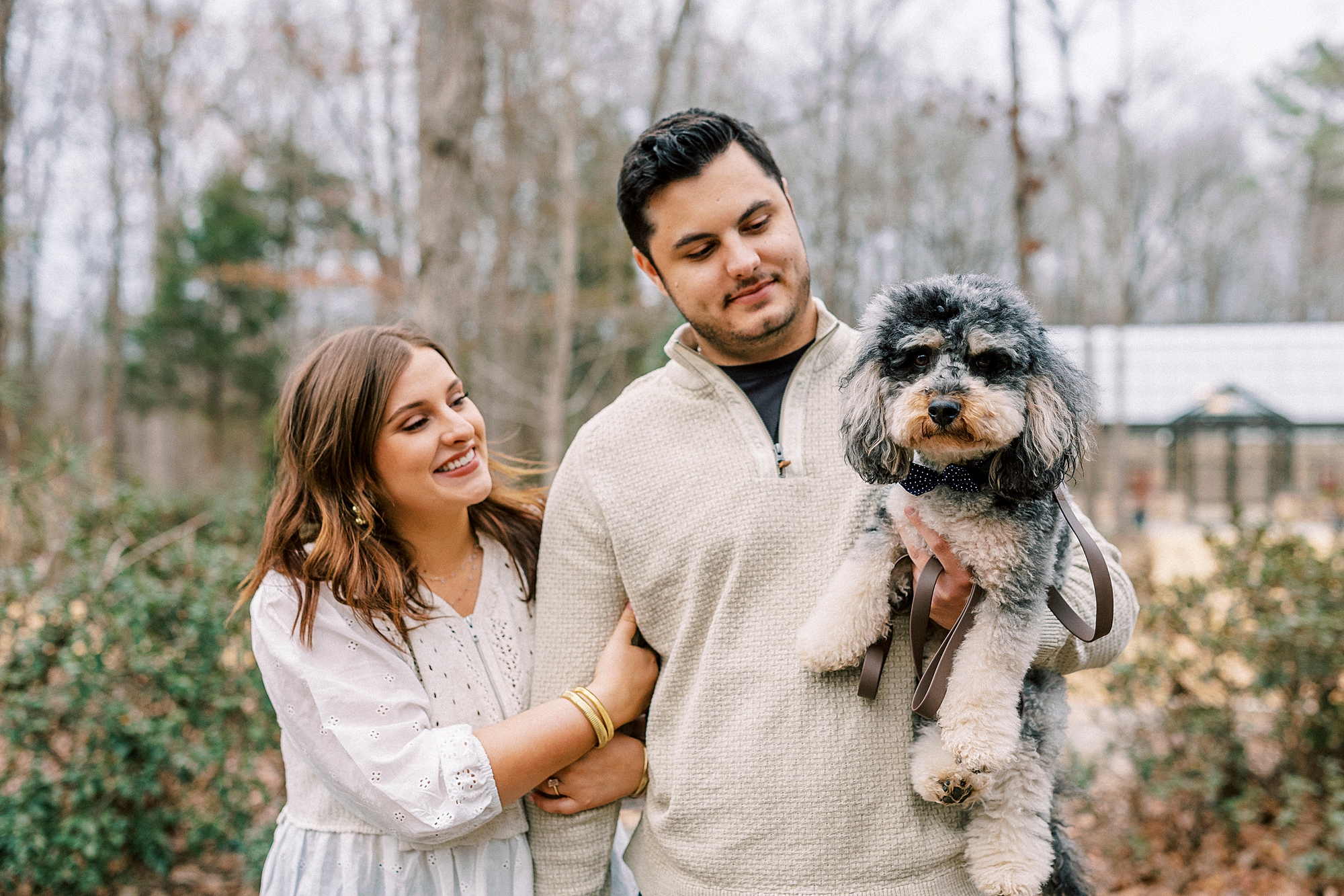 woman holds man's arm while he holds dog on farm in Monroe NC