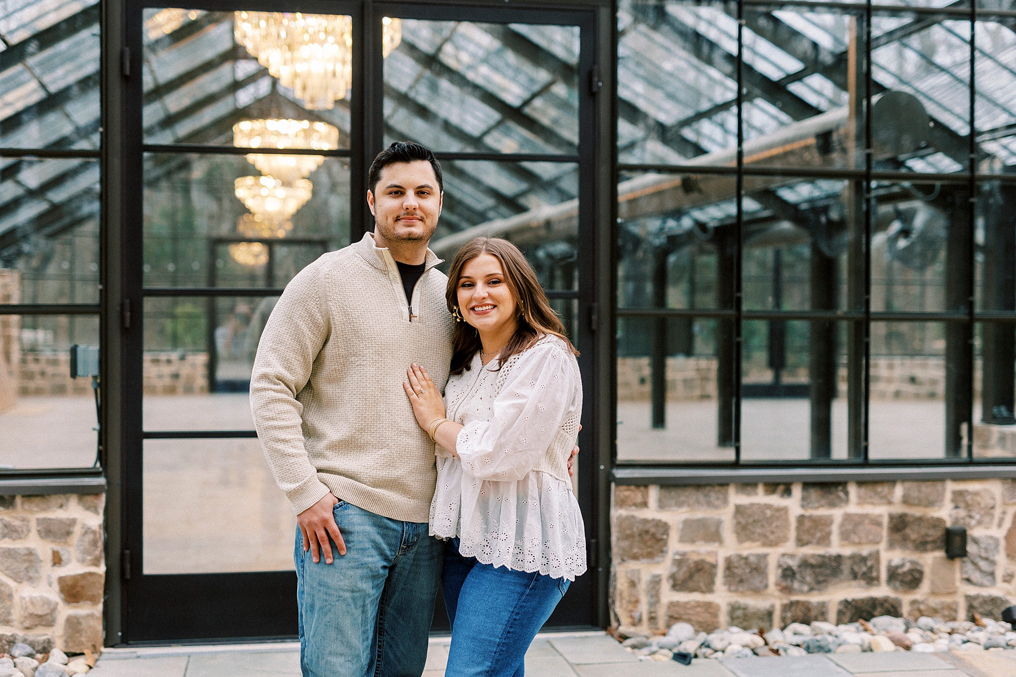 woman stands with man in front of glass greenhouse in Monroe NC