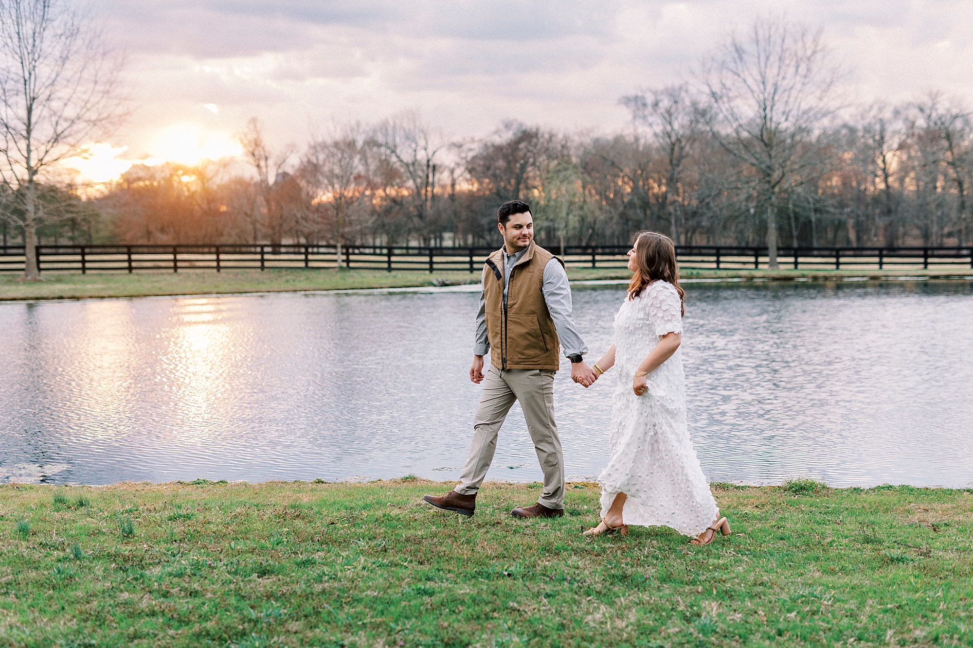 couple holds hands walking near pond at Morning Glory Farm