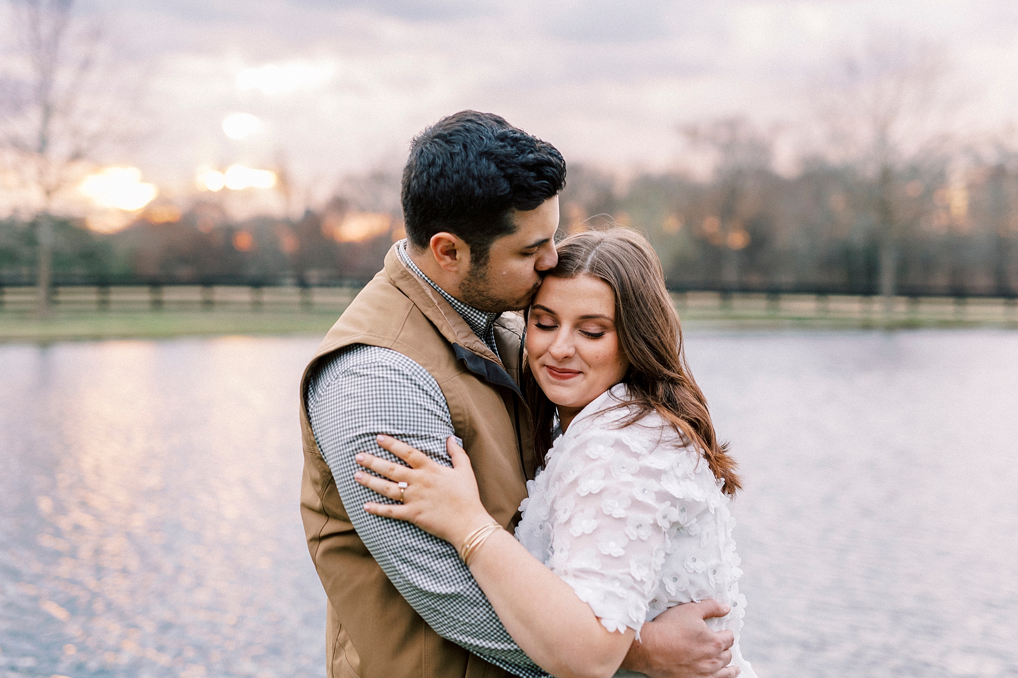 man hugs woman to his chest at sunset during engagement session at Morning Glory Farm