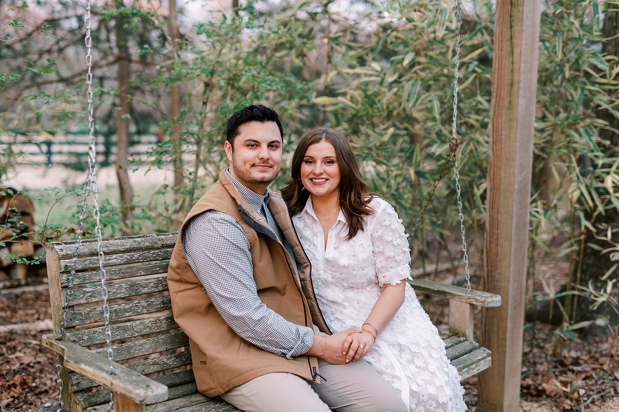 couple sits on wooden swing at Morning Glory Farm