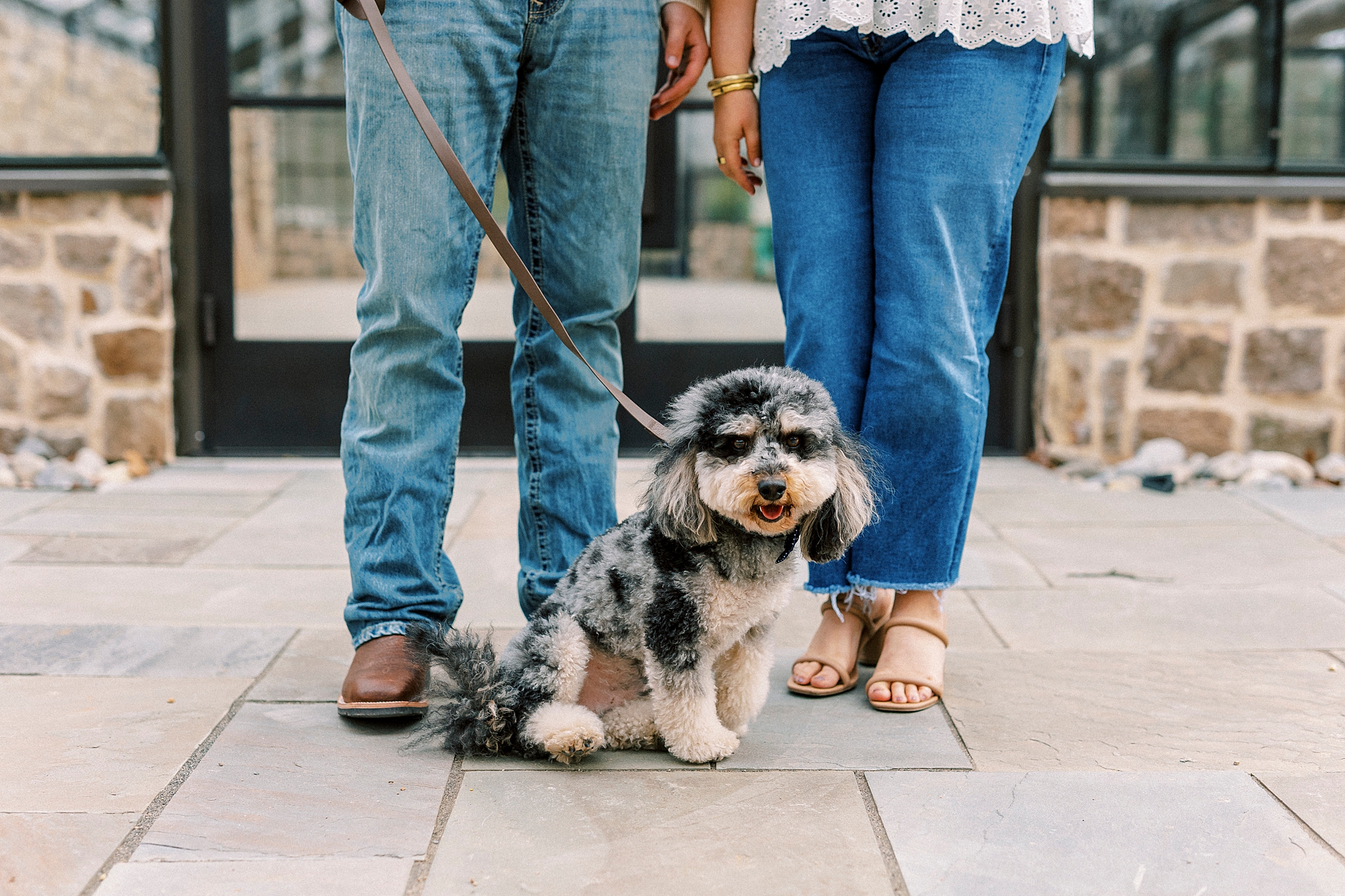 couple stands together with dog between their feet in Monroe NC