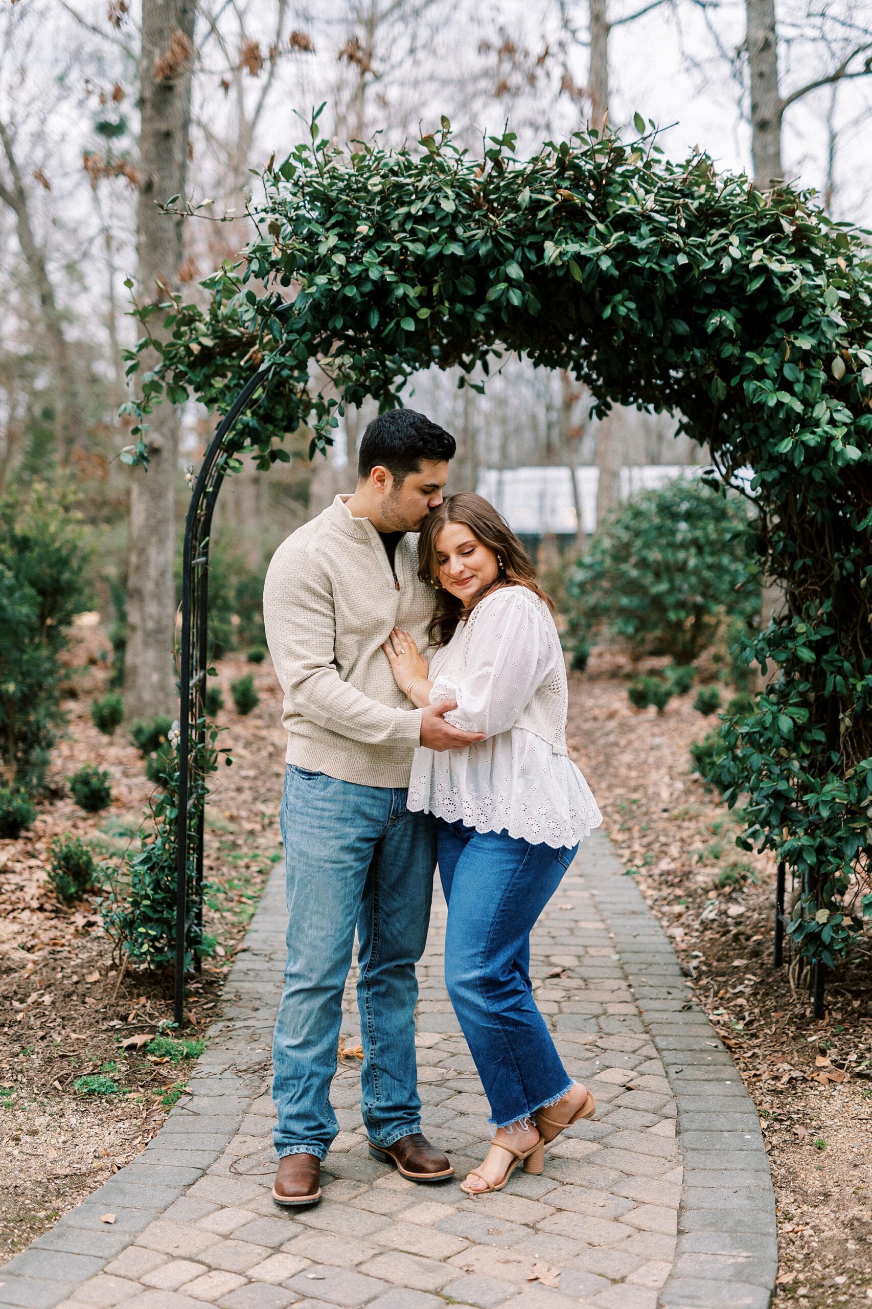 couple hugs under green arbor at Morning Glory Farm