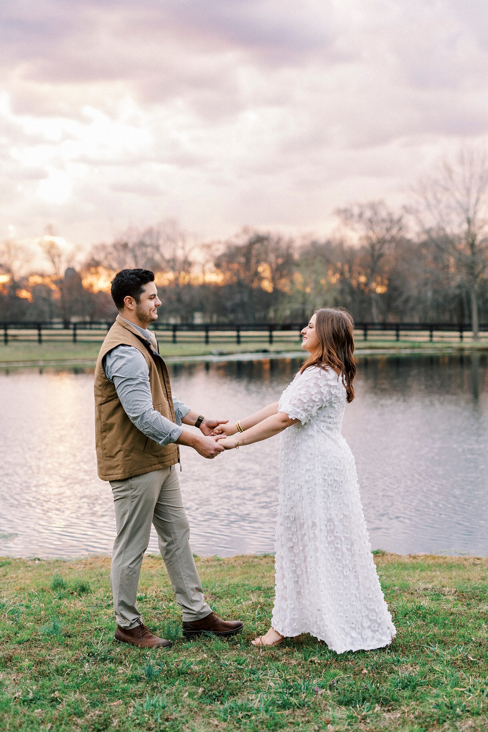couple holds hands at sunset next to pond at Morning Glory Farm
