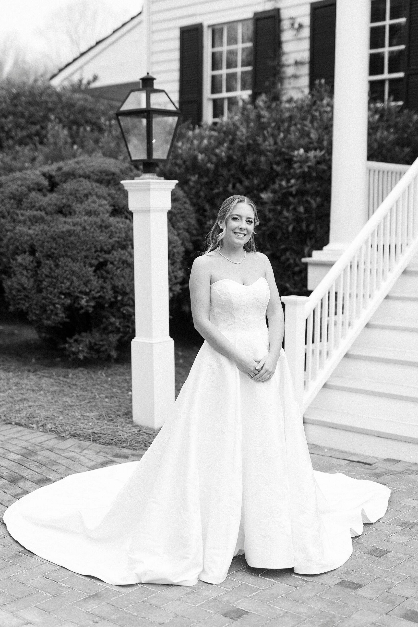 black and white portrait of bride standing outside home