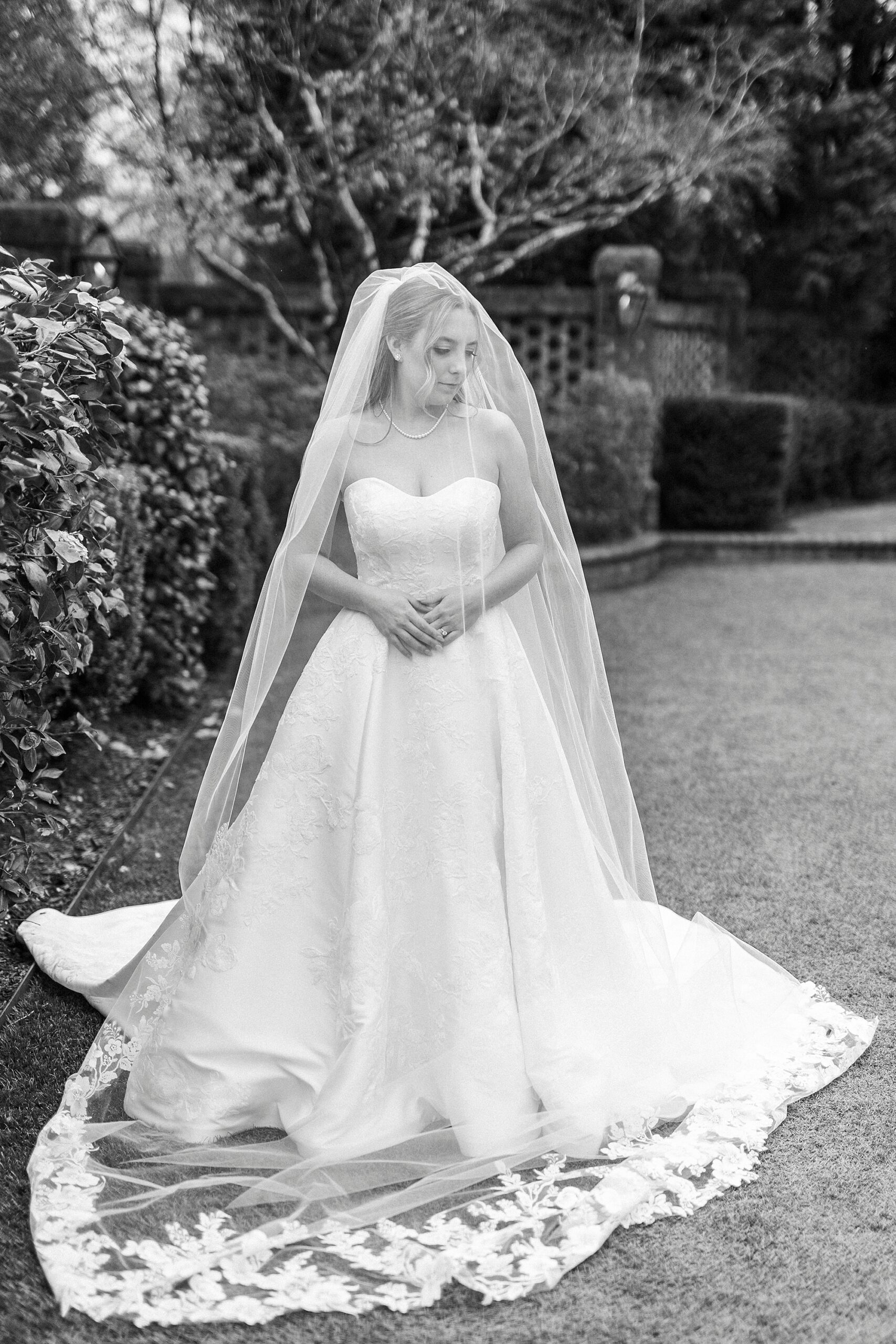 bride stands under veil with eyes closed and head turned down