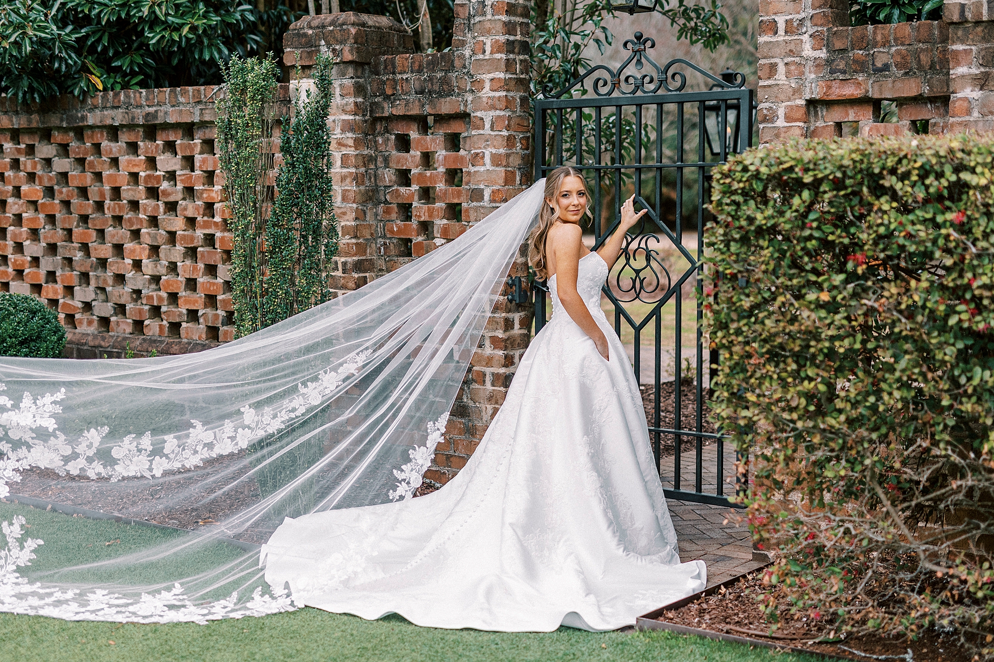 bride holds wrought iron gate in courtyard at the Sutherland in Wake Forest NC