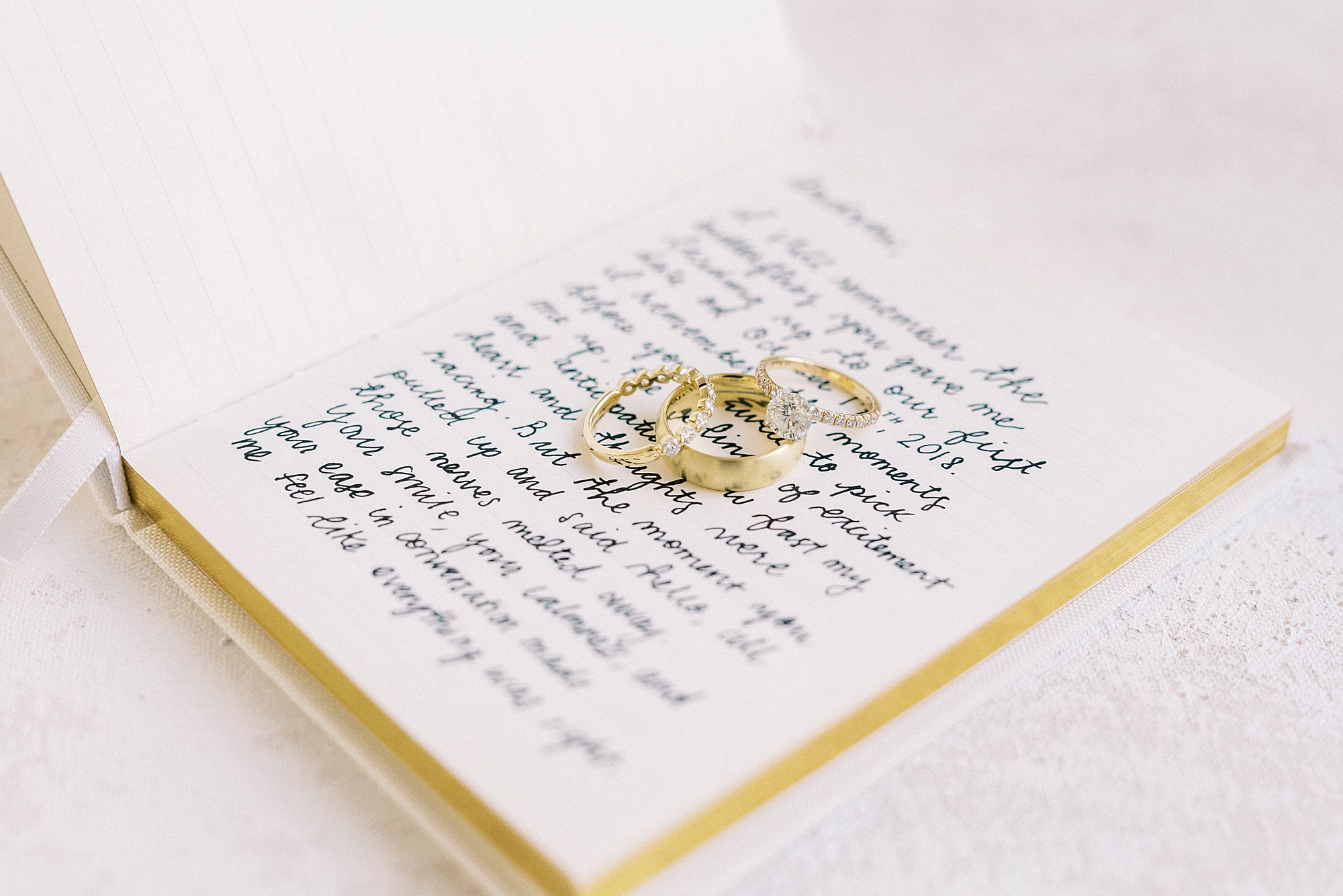 gold wedding bands rest on vow booklet before wedding in North Carolina