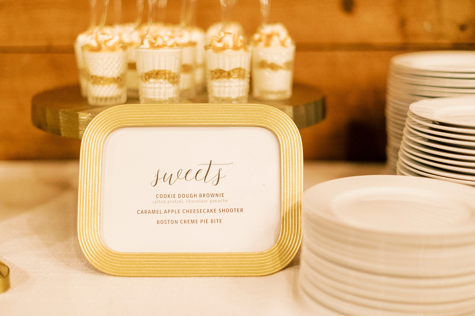 mini dessert display on gold cake stand and gold framed sweets sign for wedding reception 