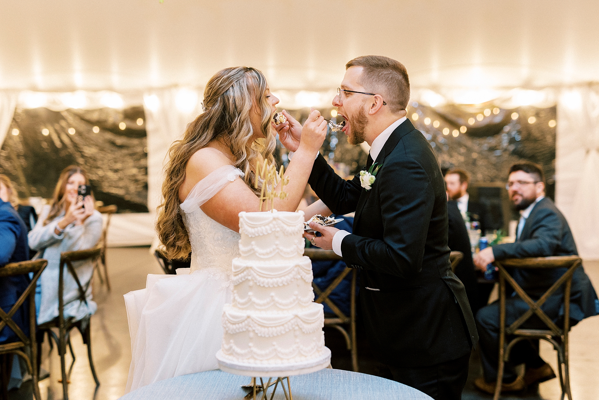 bride and groom cut wedding cake and feed each other a piece
