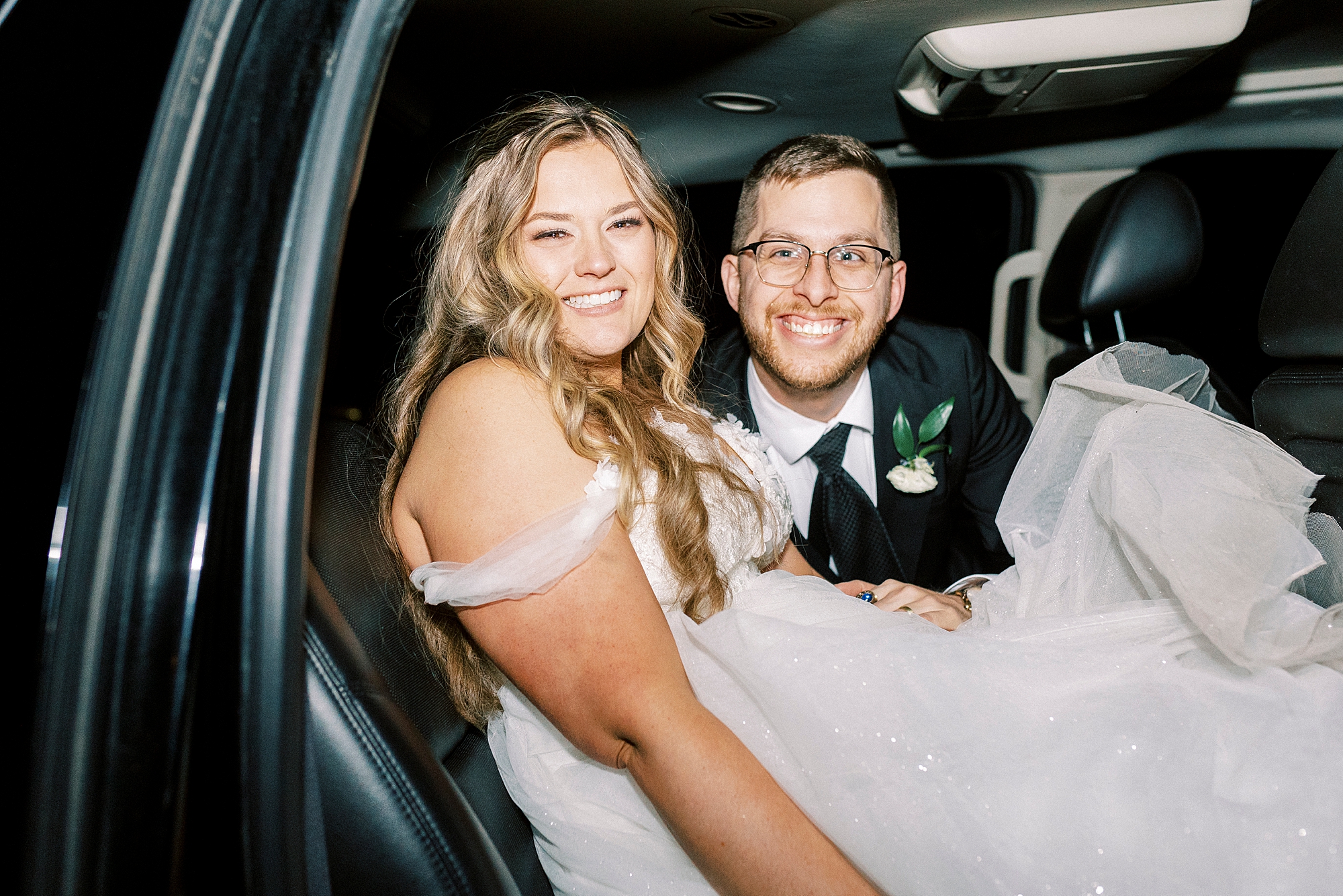 bride and groom sit inside limo leaving wedding reception 