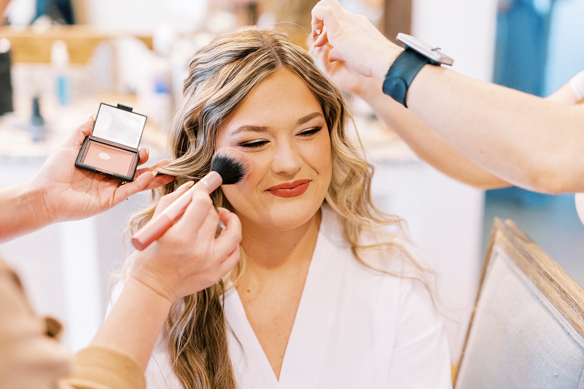 bride sits getting makeup put on during prep at Summerfield Farms