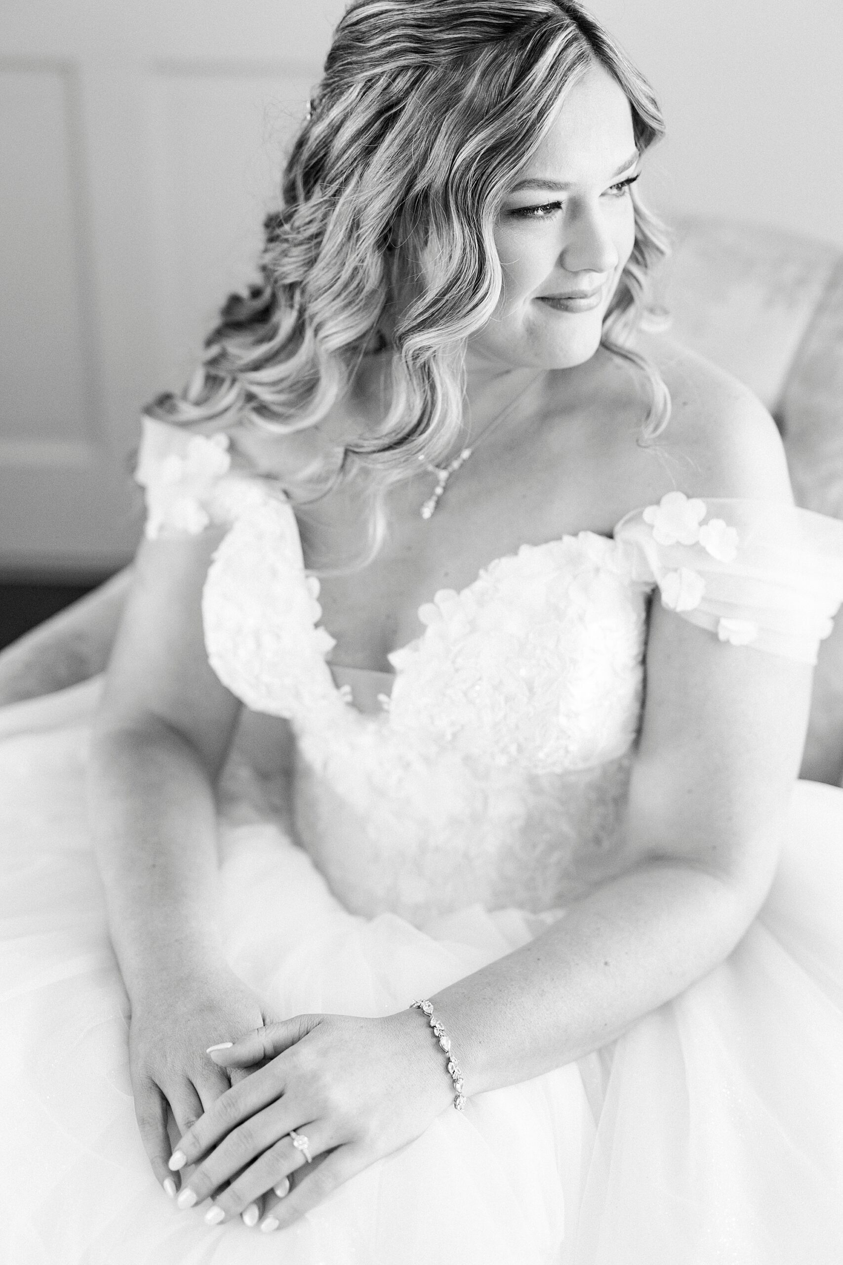 bride sits with hands in lap in wedding gown in suite at Summerfield Farms