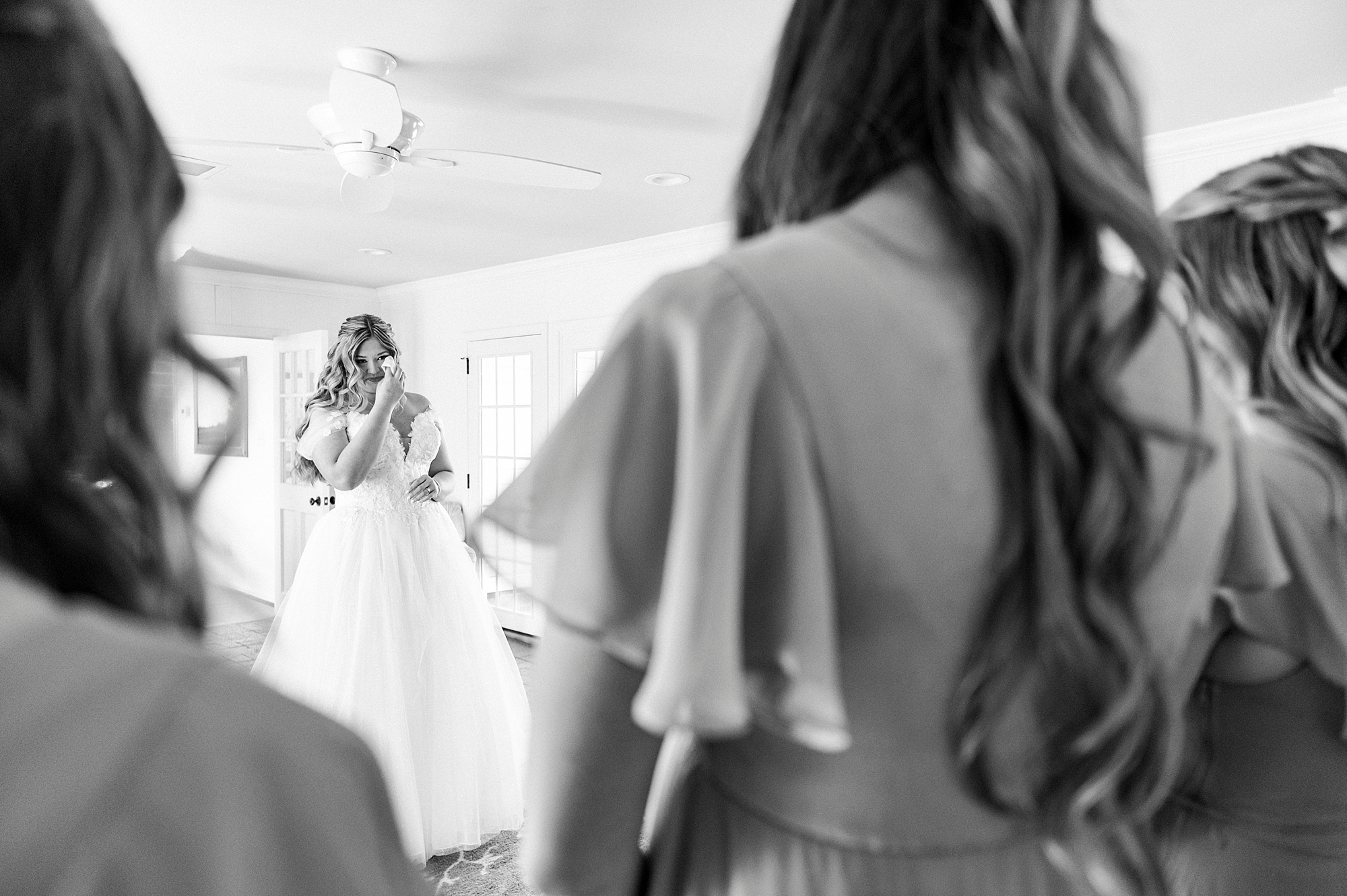photo of bride over bridesmaids' shoulders as she cries during first look