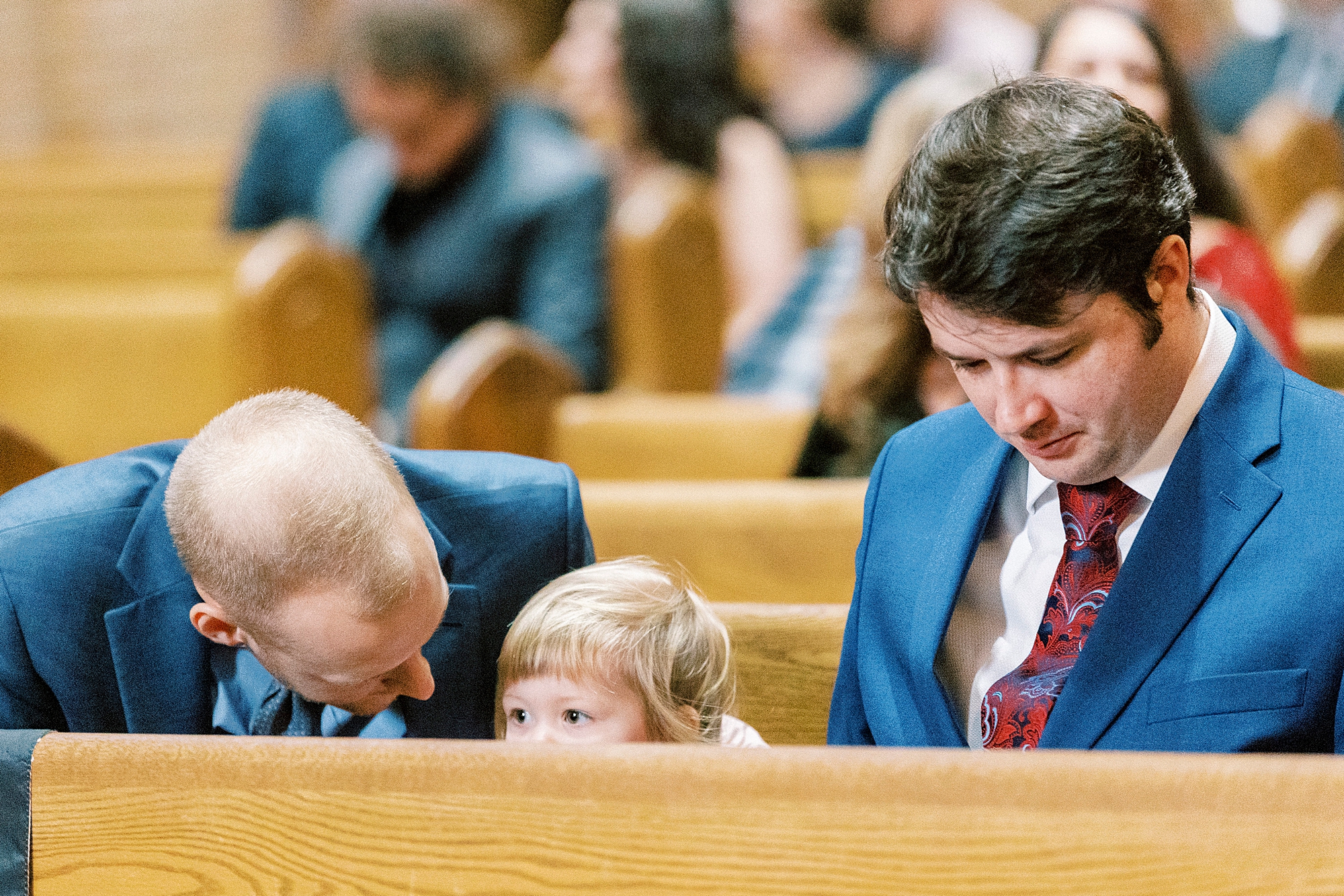 father prays in pew with young child during ceremony 