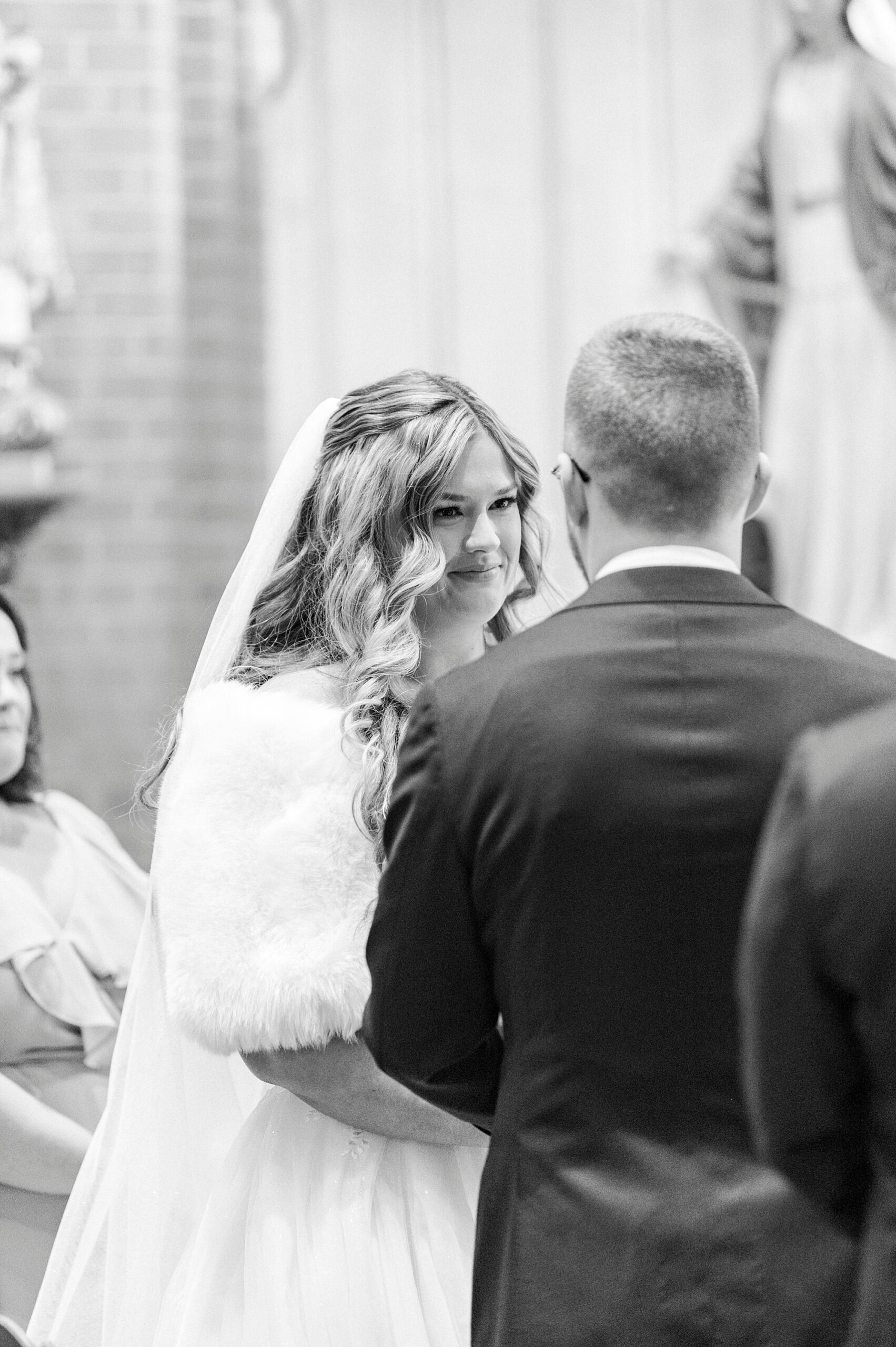 bride looks at groom holding his hand during traditional church wedding at Our Lady of Grace