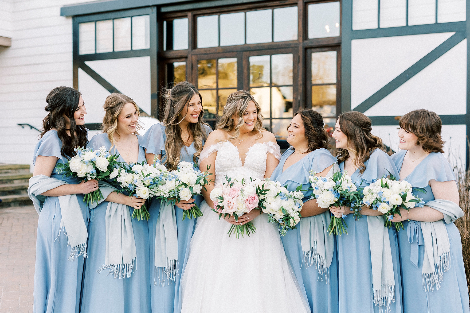 bride stands with bridesmaids in light blue gowns outside Summerfield Farms