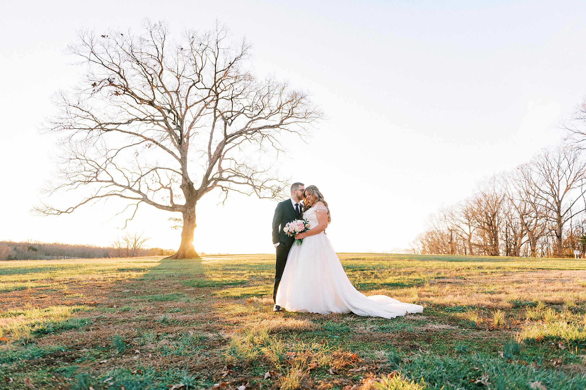bride and groom stand under oak tree at Summerfield Farms