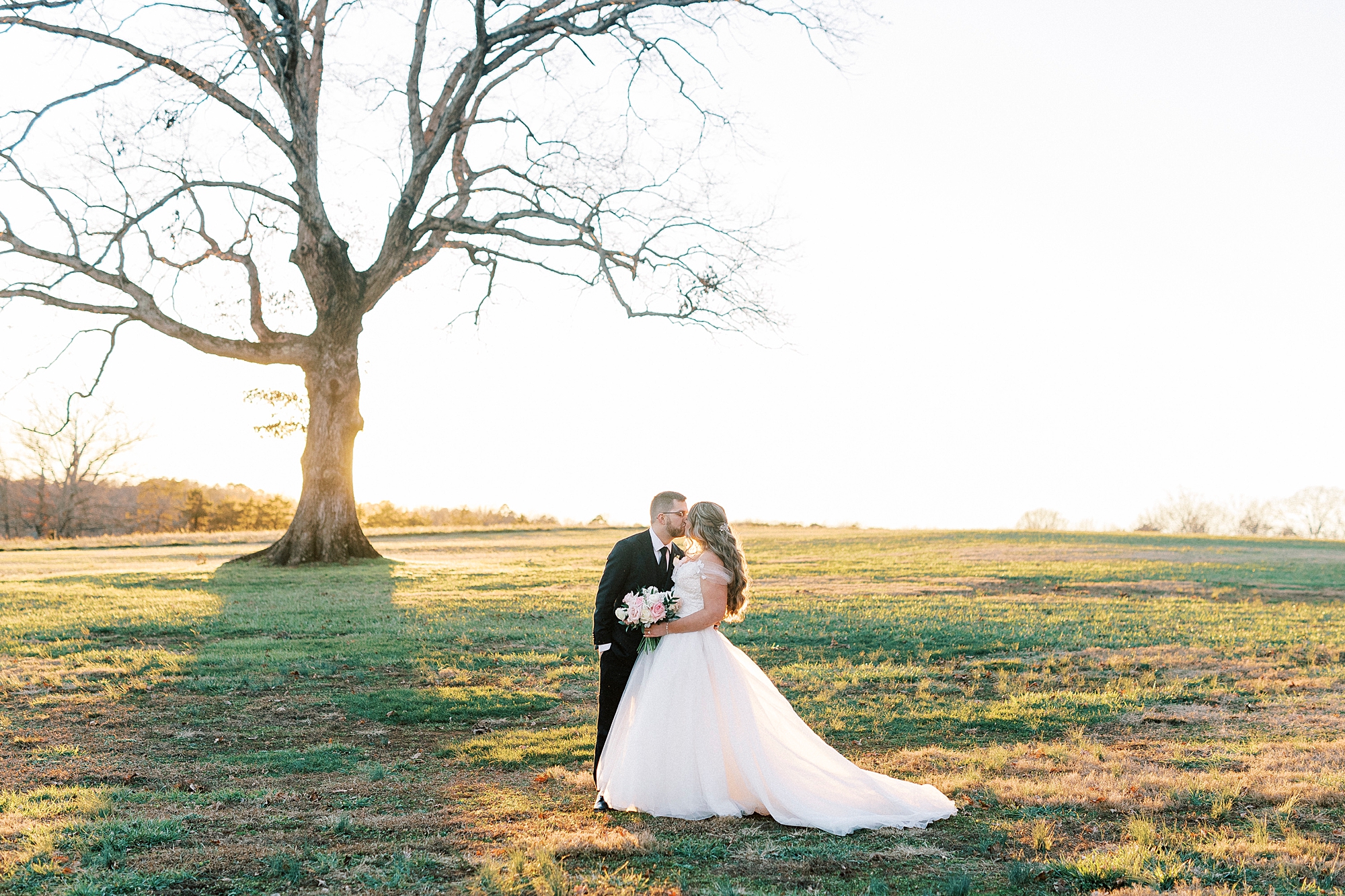 bride and groom kiss in front of oak tree at Summerfield Farms