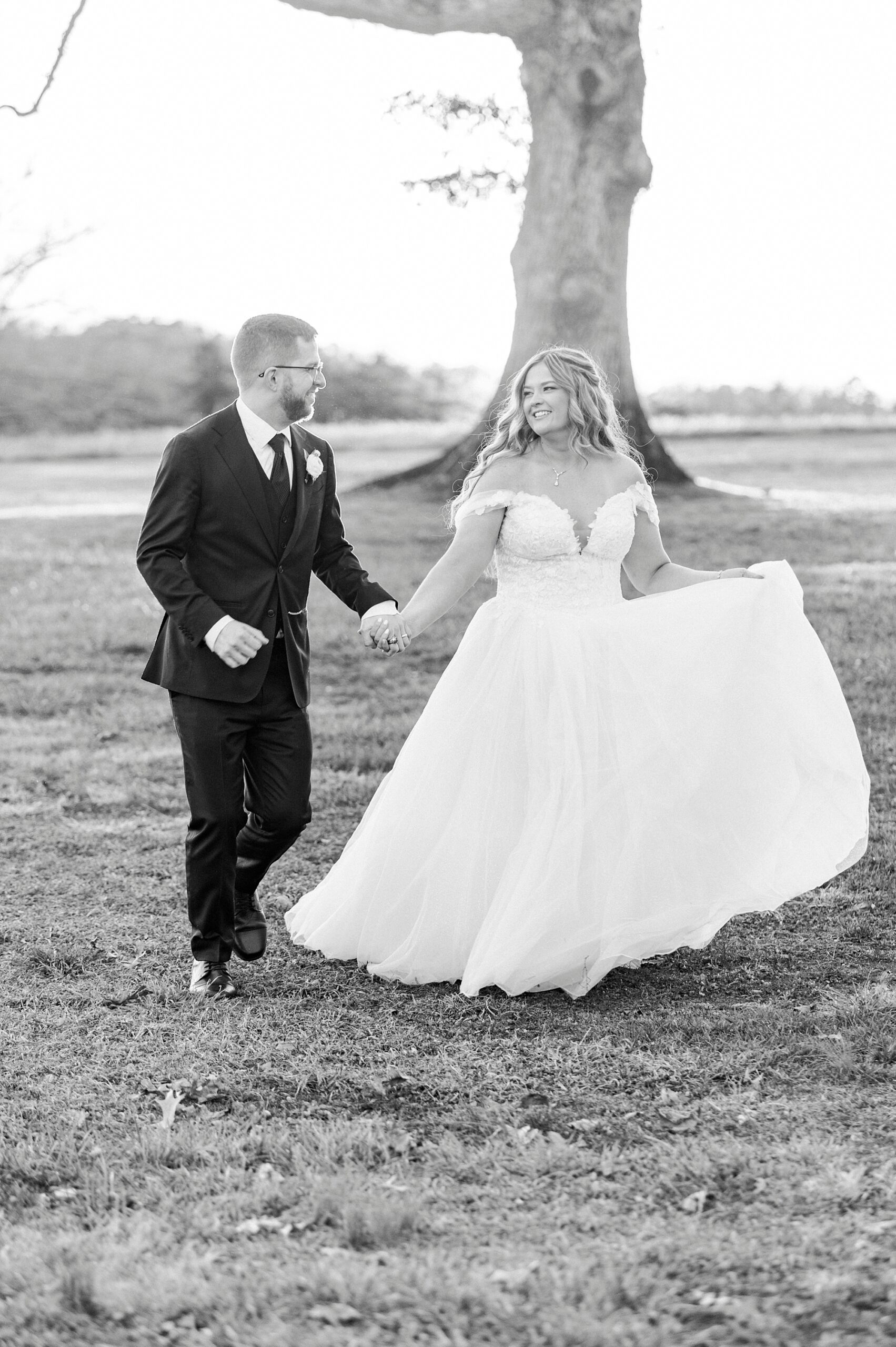 bride and groom hold hands walking on lawn outside Summerfield Farms