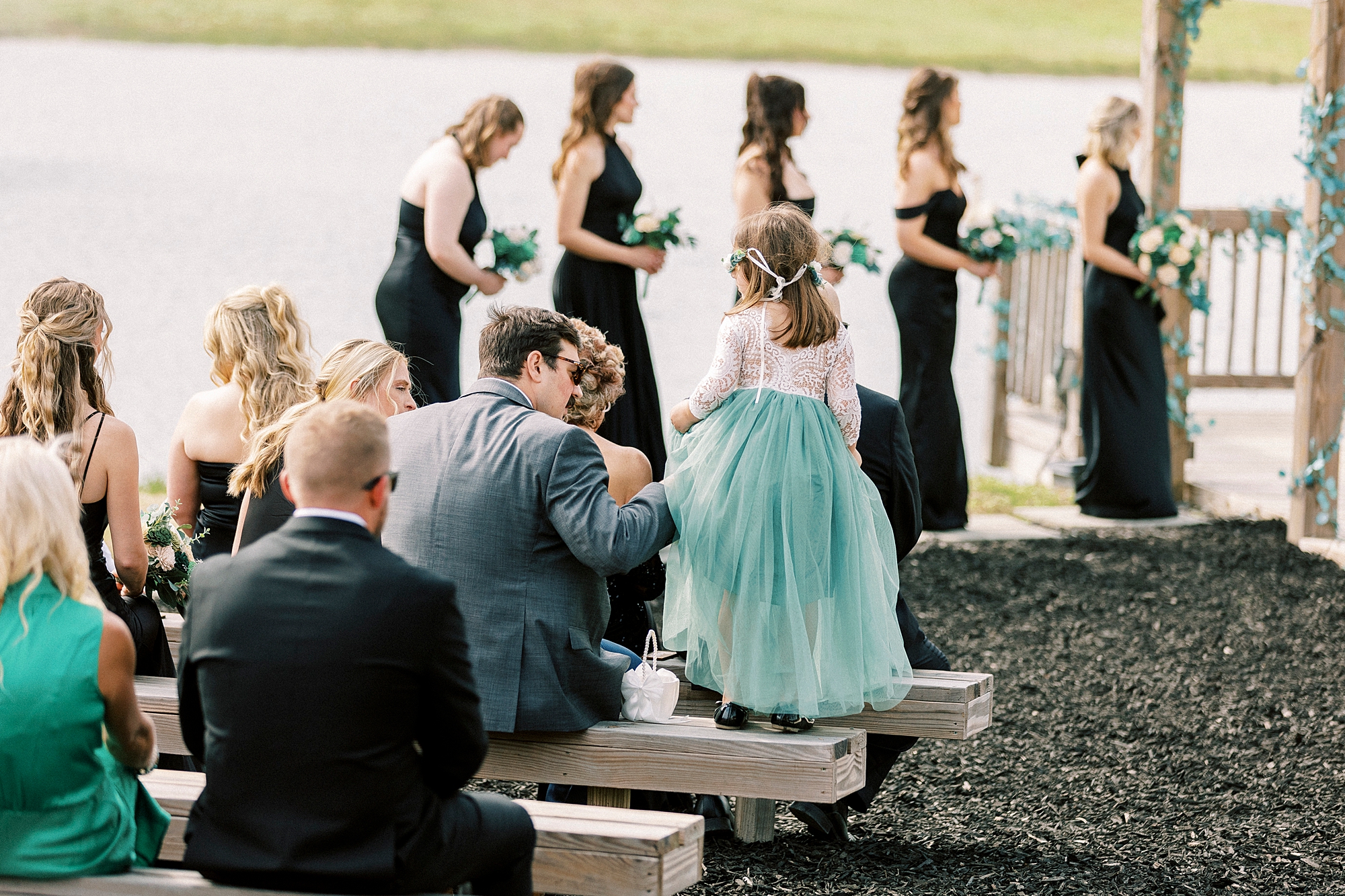 flower girl stands on wooden bench at ceremony site 
