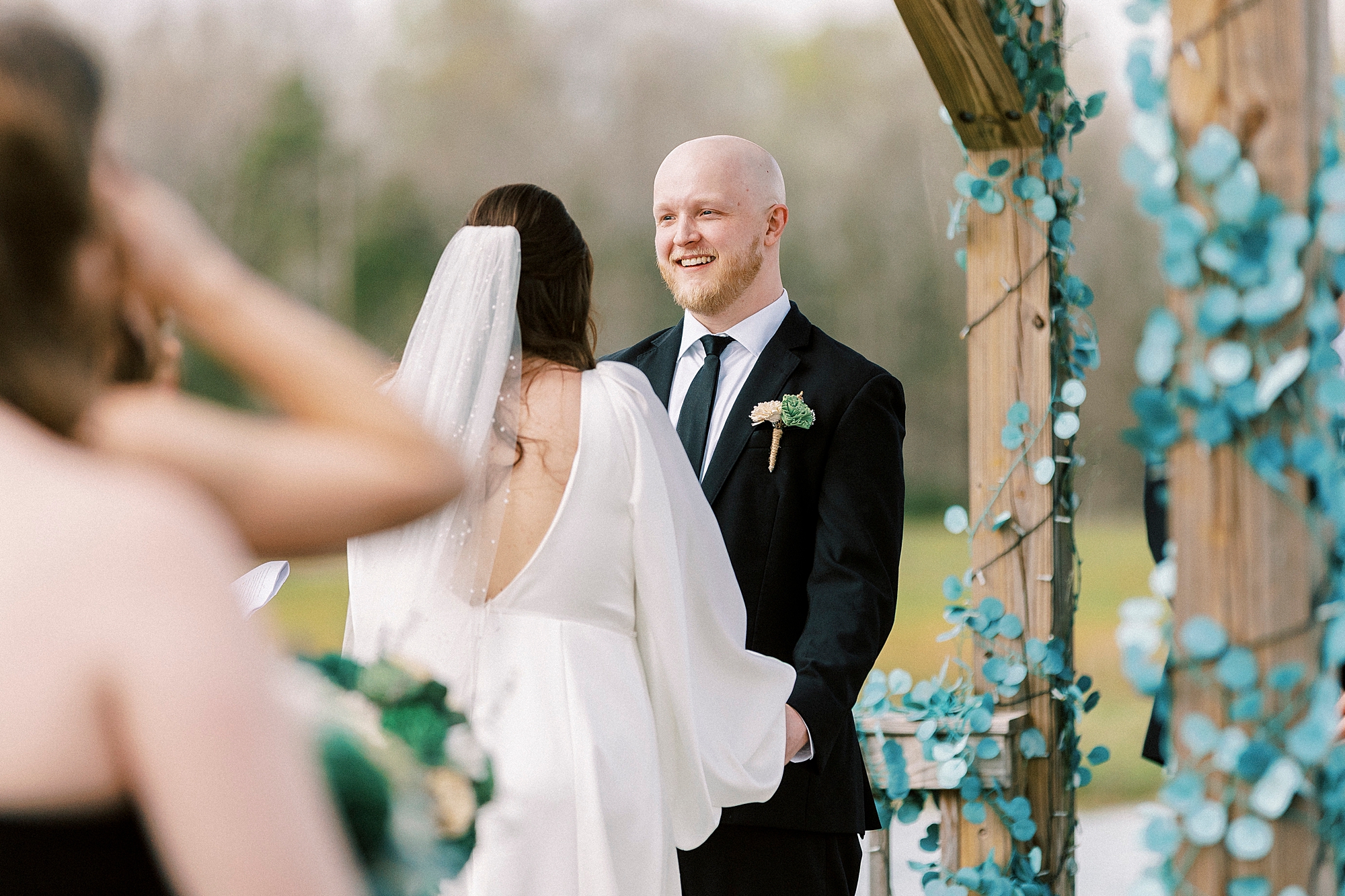 groom smiles at bride during ceremony at Sixty Acres Farm