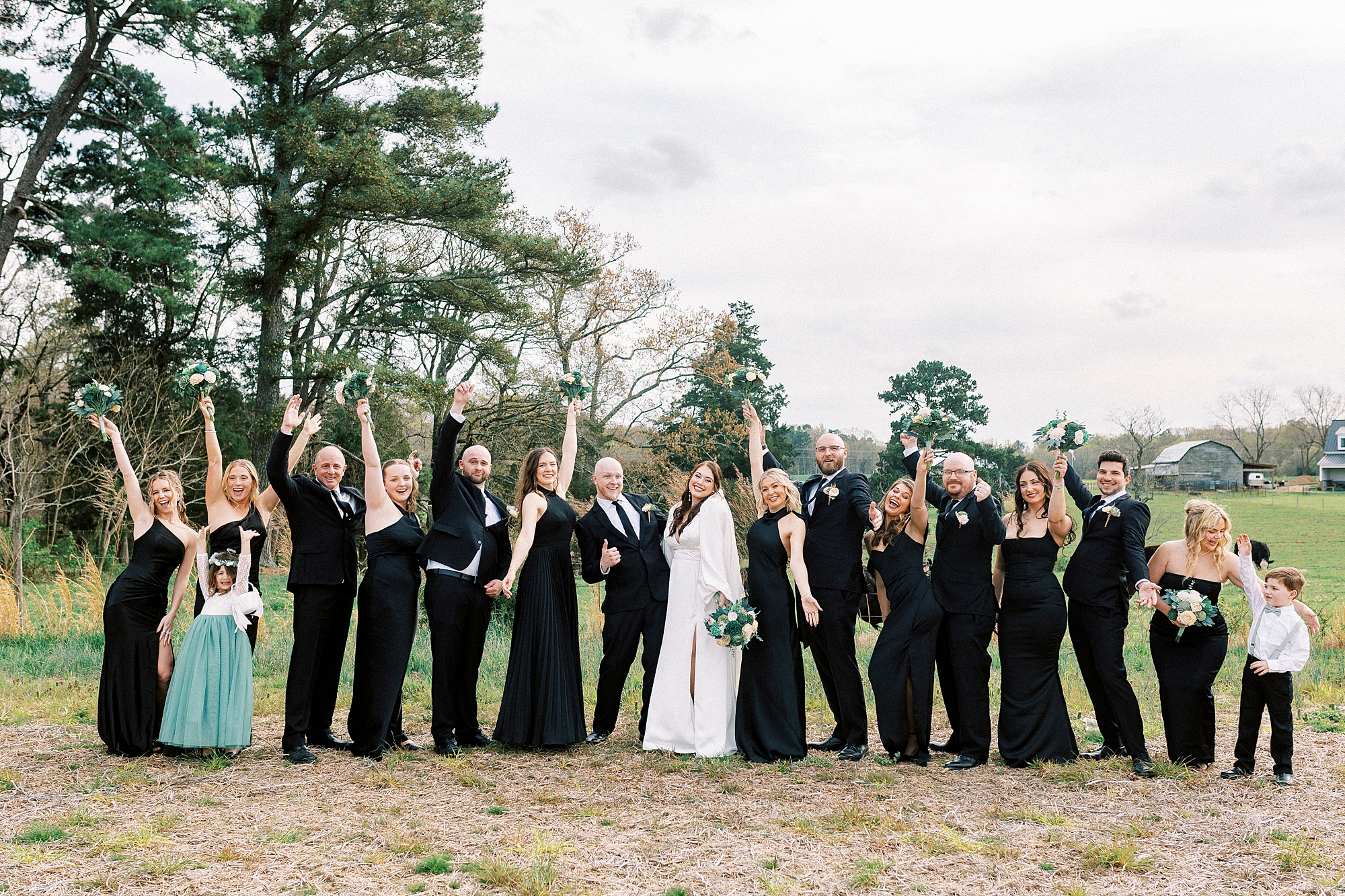 bride and bridesmaids cheer on edge of pasture at Sixty Acres Farm