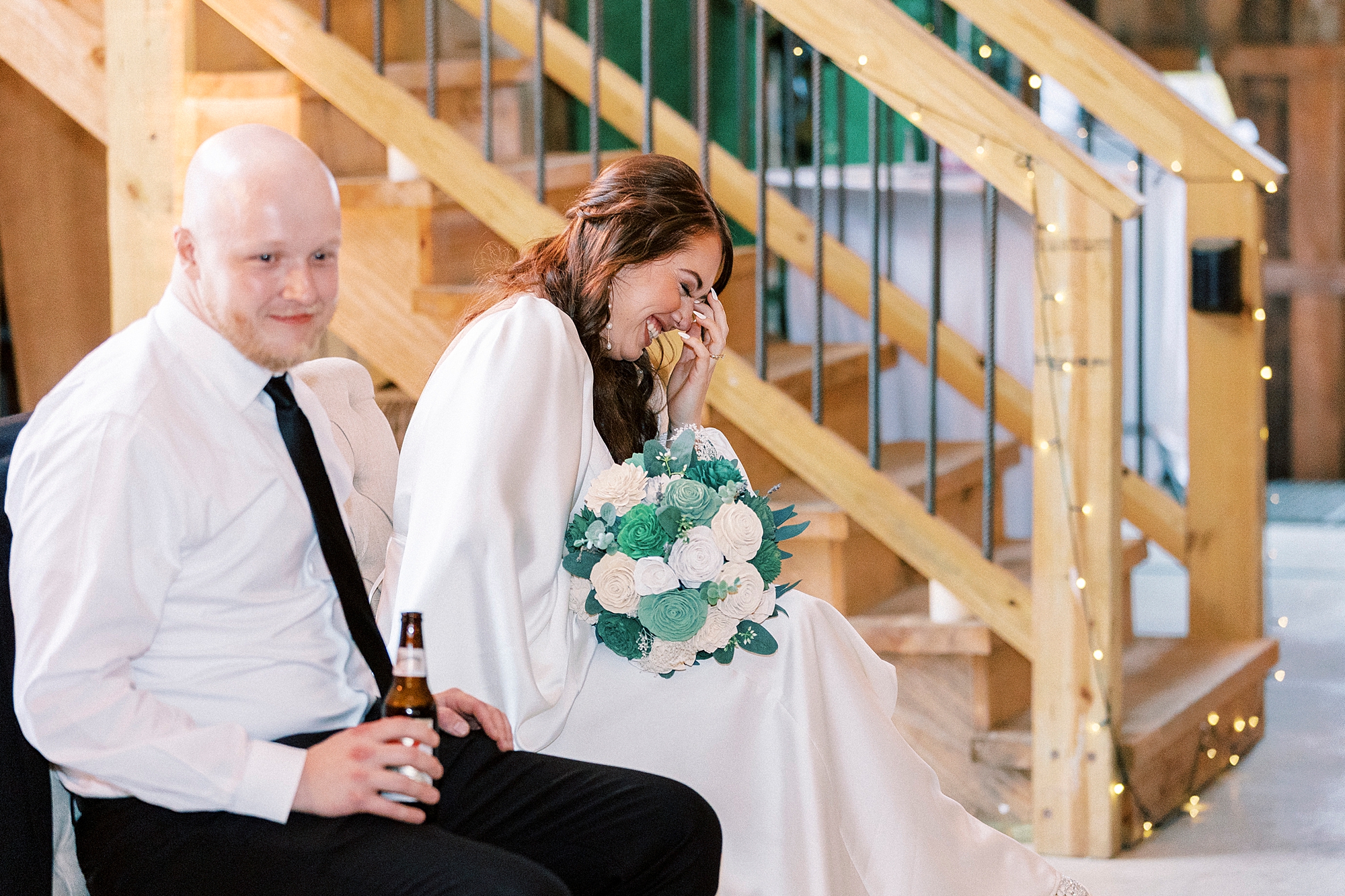 bride holds hands with groom laughing during speeches at during wedding reception in Mount Pleasant NC