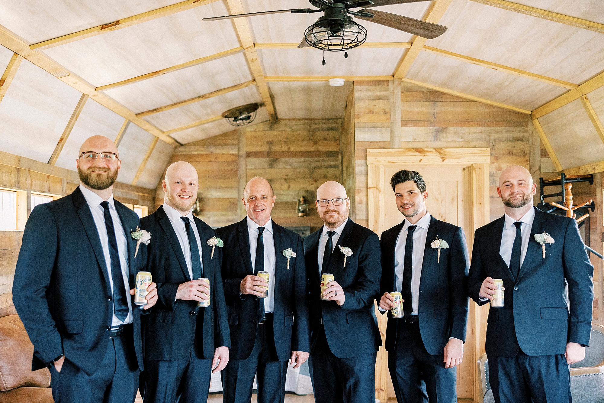 groom and groomsmen pose in attic of barn at Sixty Acres Farm