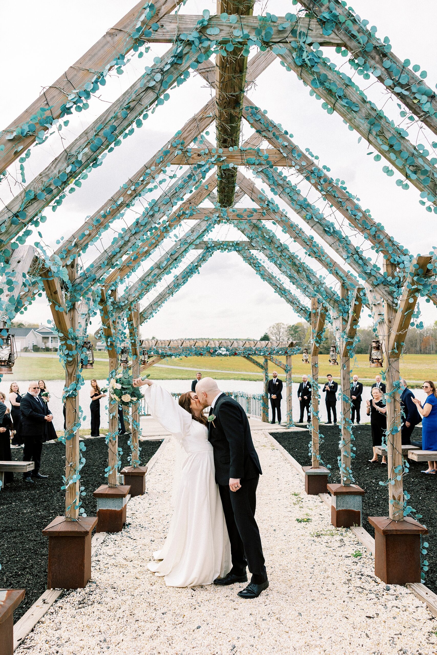 newlyweds kiss in aisle leaving ceremony along the pond at Sixty Acres Farm