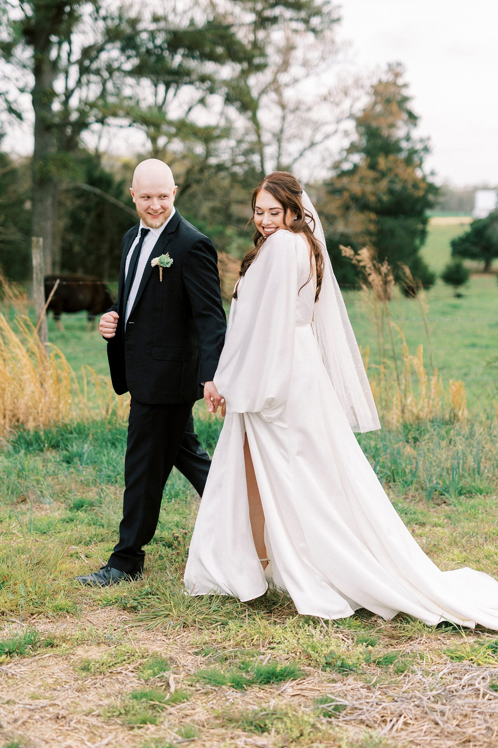 newlyweds hold hands walking while bride looks over shoulder 