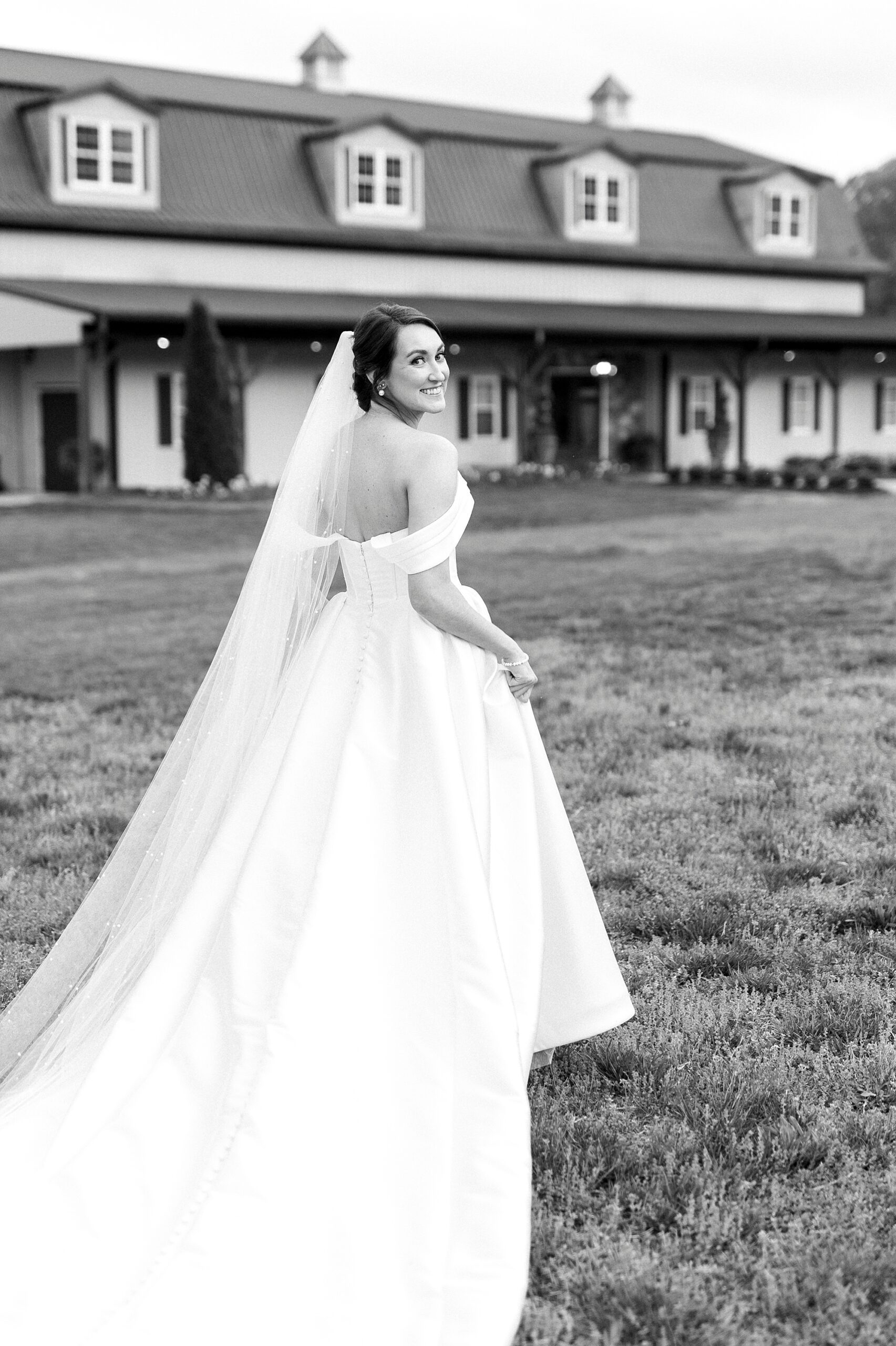 bride lifts up skirt walking towards farmhouse at Low Meadows Estate
