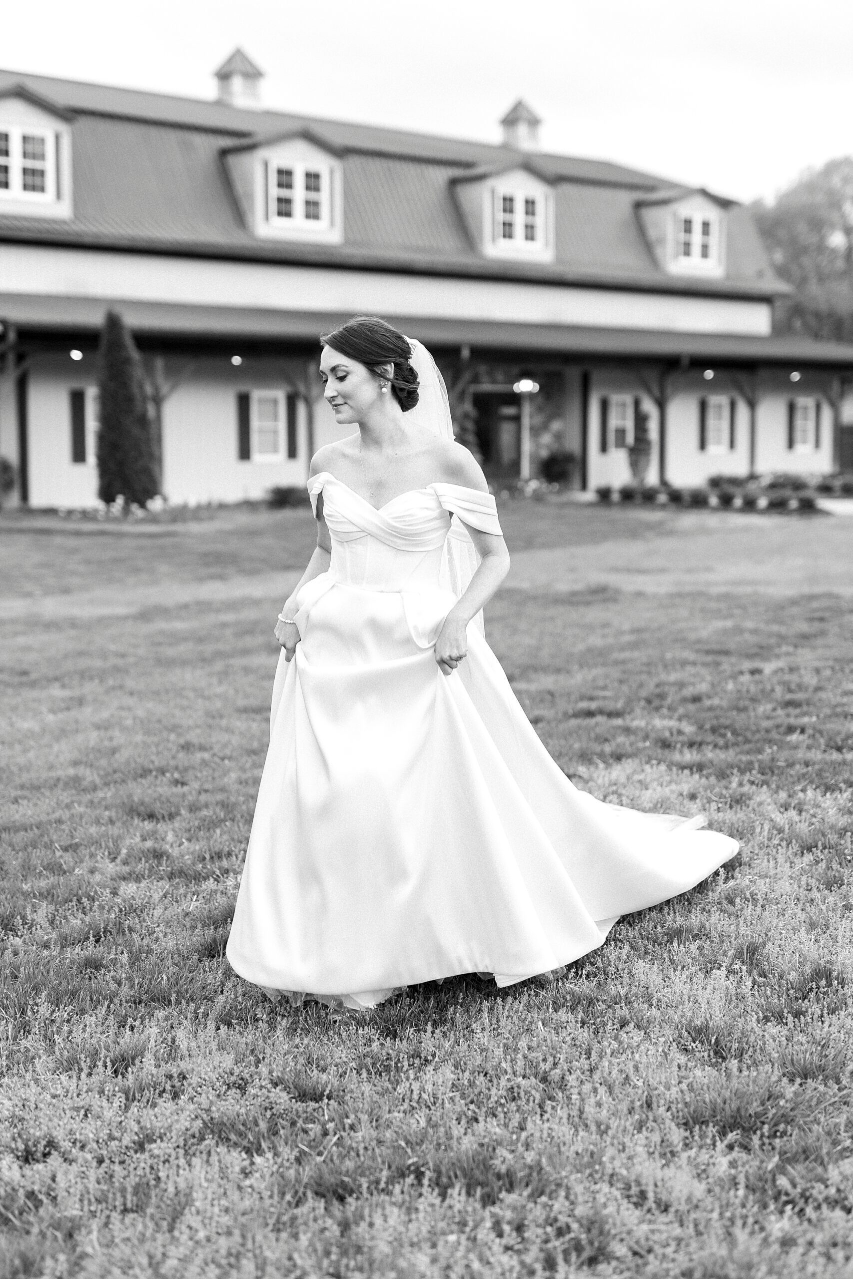 bride picks up skirt of wedding dress walking down hill at Low Meadows Estate