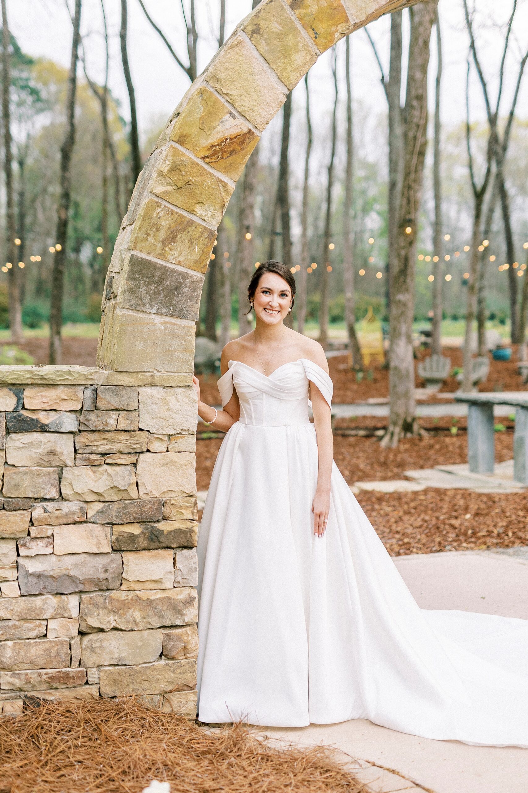 bride leans against stone arbor at Low Meadows Estate