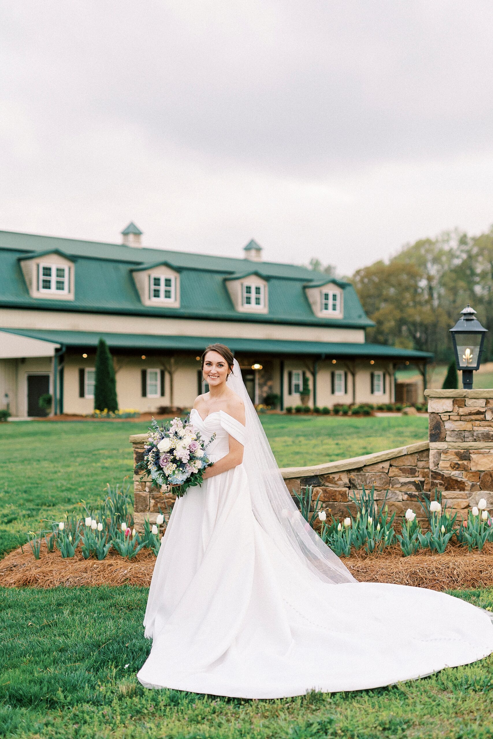 bride poses by green and tan farmhouse in Mount Holly NC