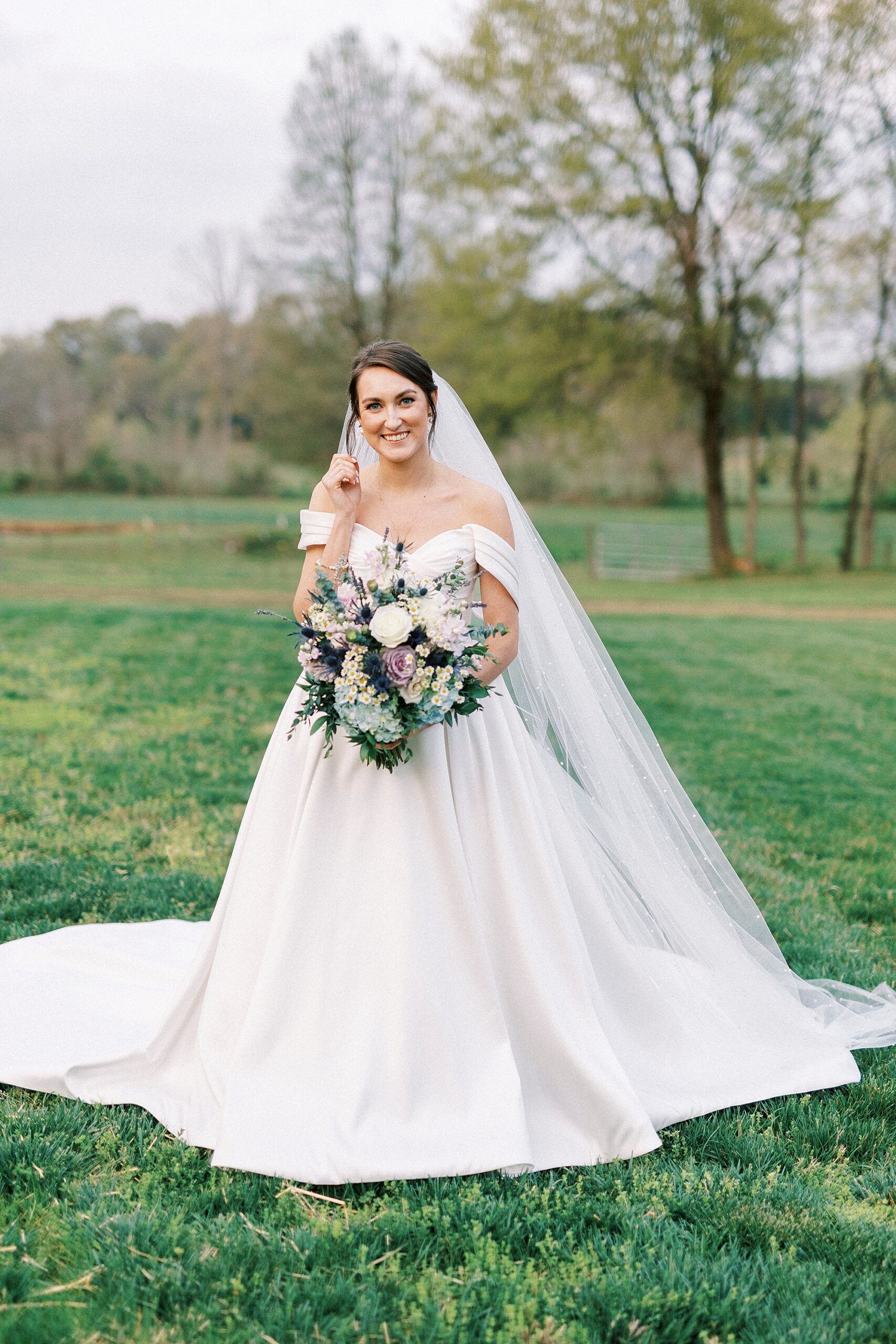 bride stands on lawn with spring bouquet 