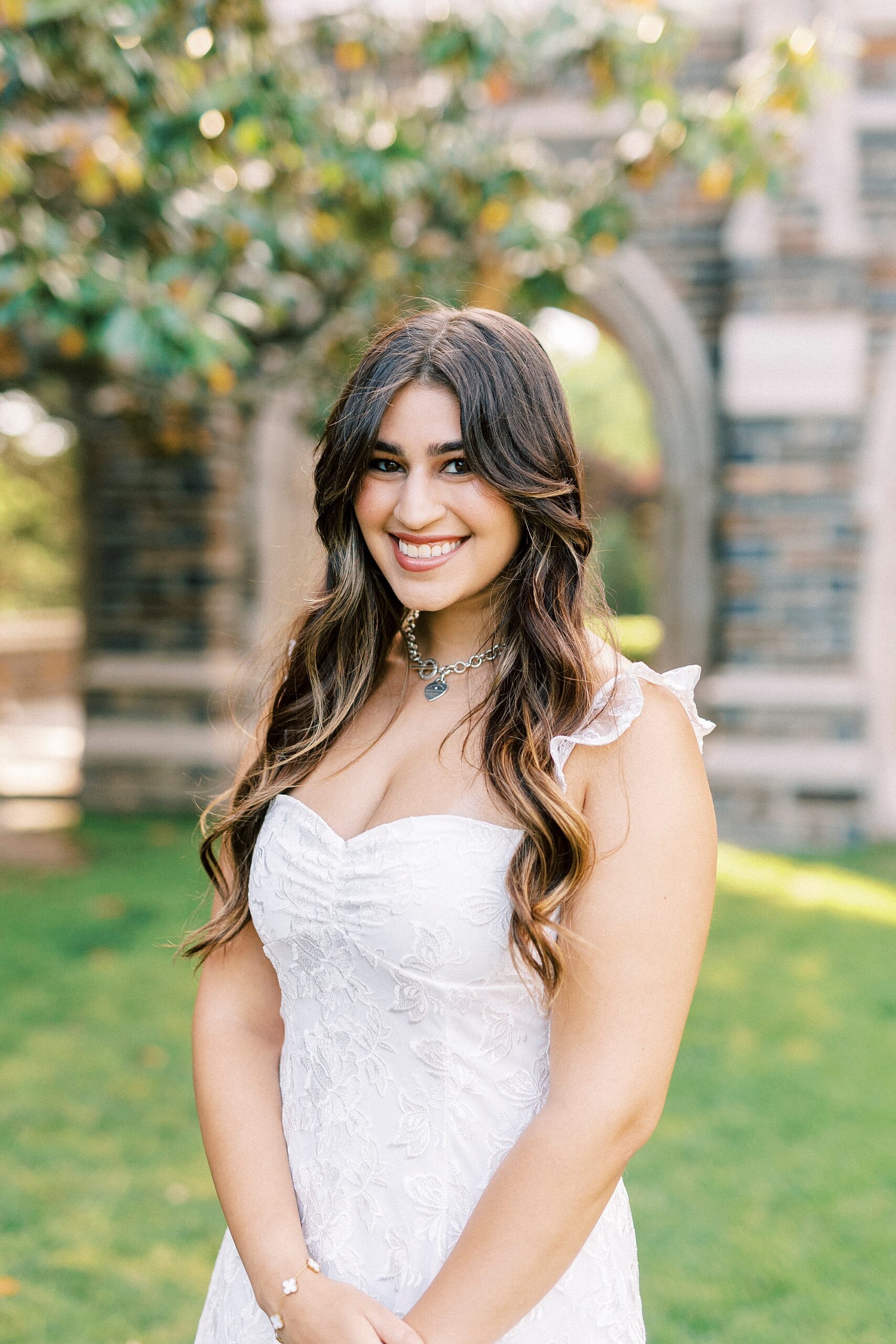 college senior in white dress smiles outside Duke Chapel