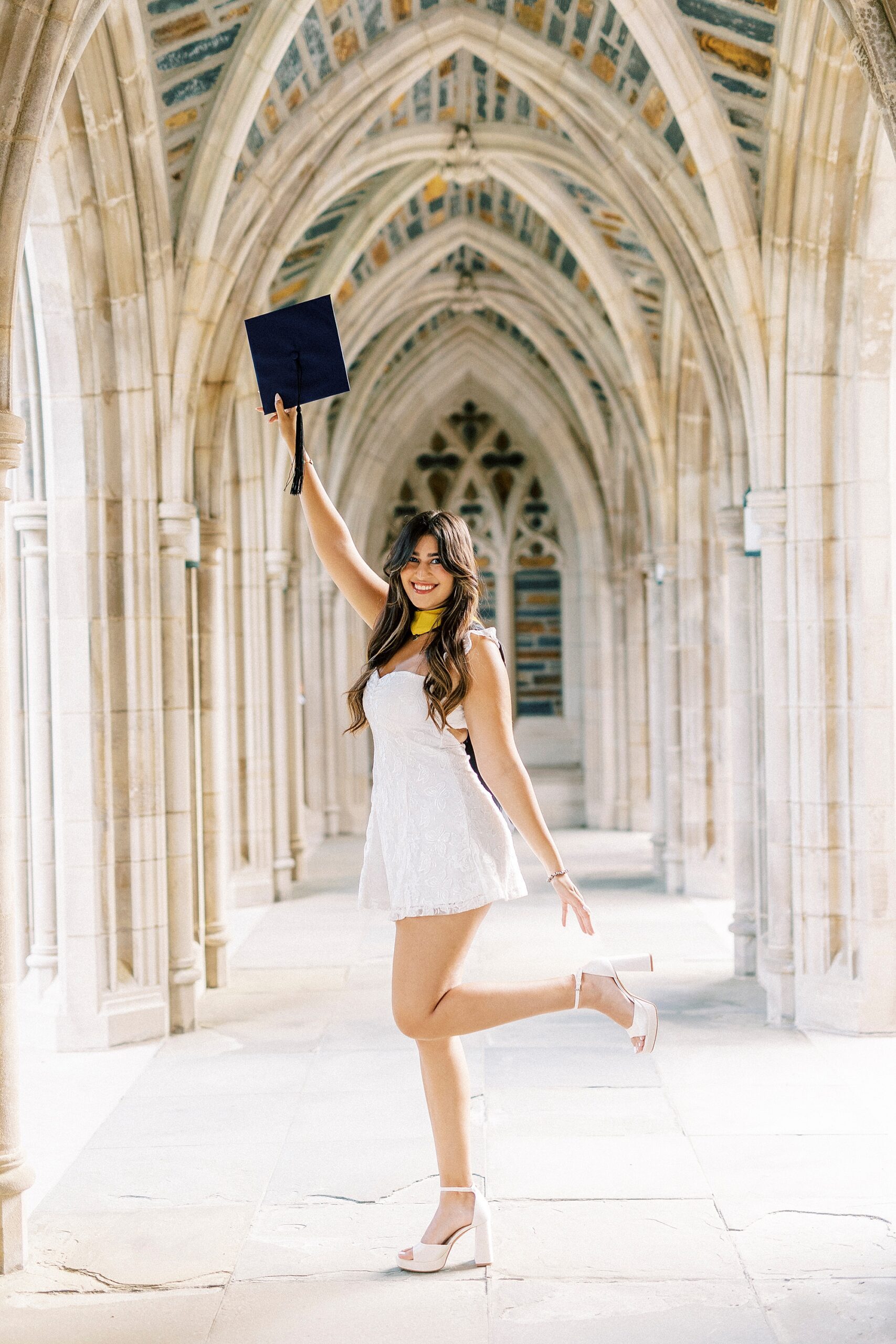 senior holds up blue cap during Duke Chapel graduation portraits
